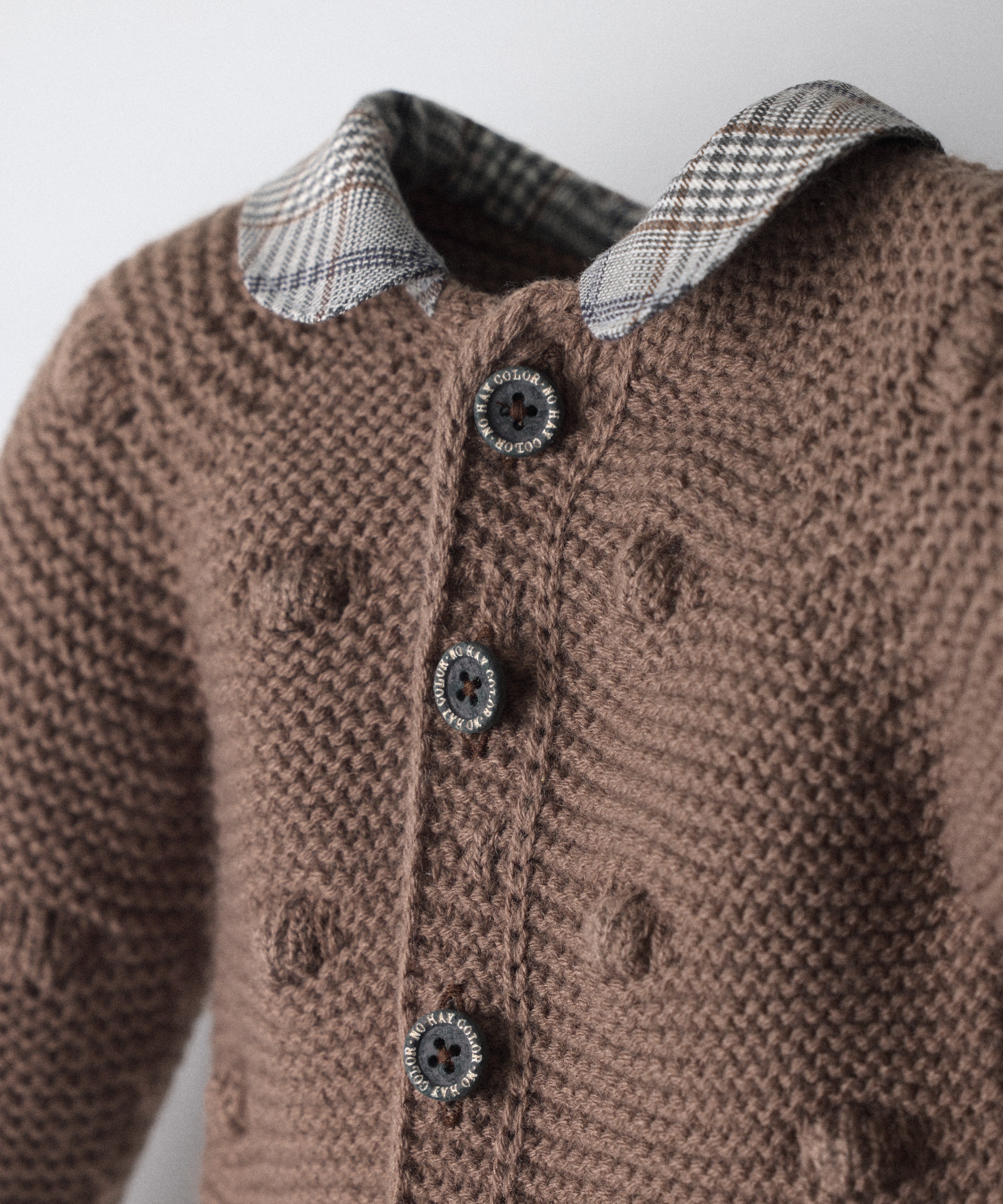 Chaqueta de punto marrón con bodoques, botones OEKO TEX en contraste y cuello con tejido de cuadros GOTS. Un diseño único de Kala para bebé