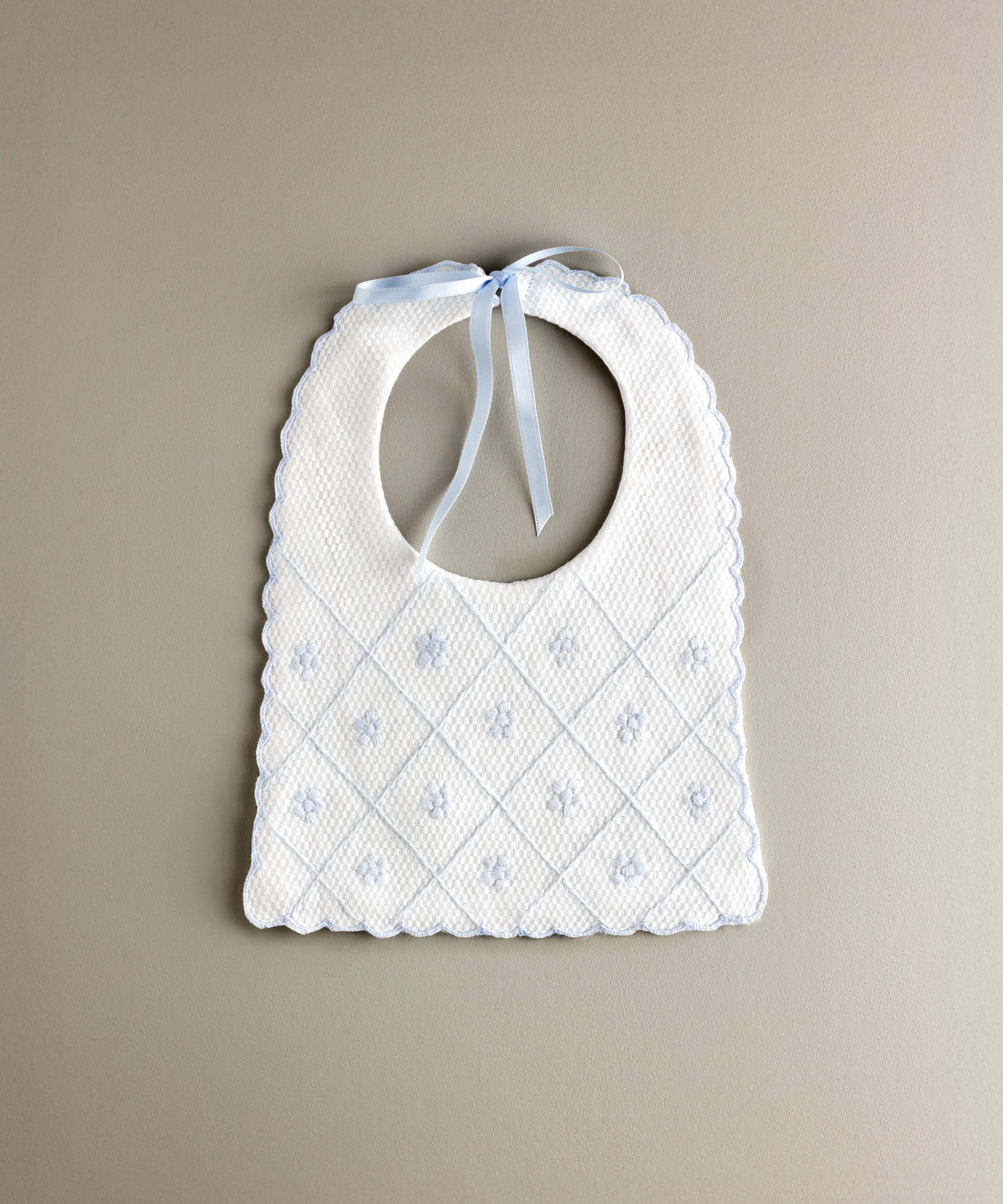 Babero de bebé confeccionado en piqué de algodón con bordado en cuadrícula y flores en color azul empolvado.R.478SBL