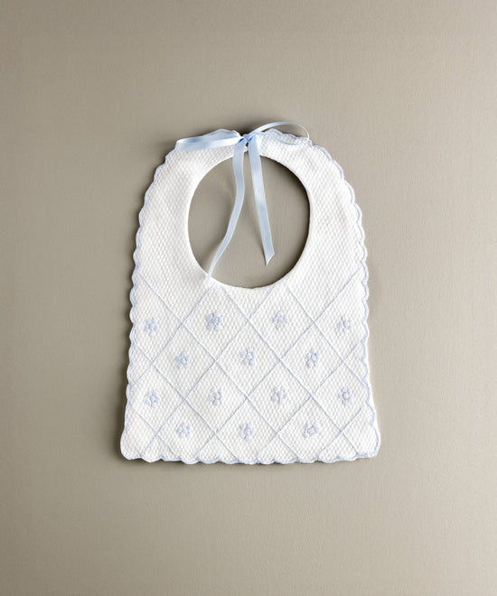 Babero de bebé confeccionado en piqué de algodón con bordado en cuadrícula y flores en color azul empolvado.R.478SBL
