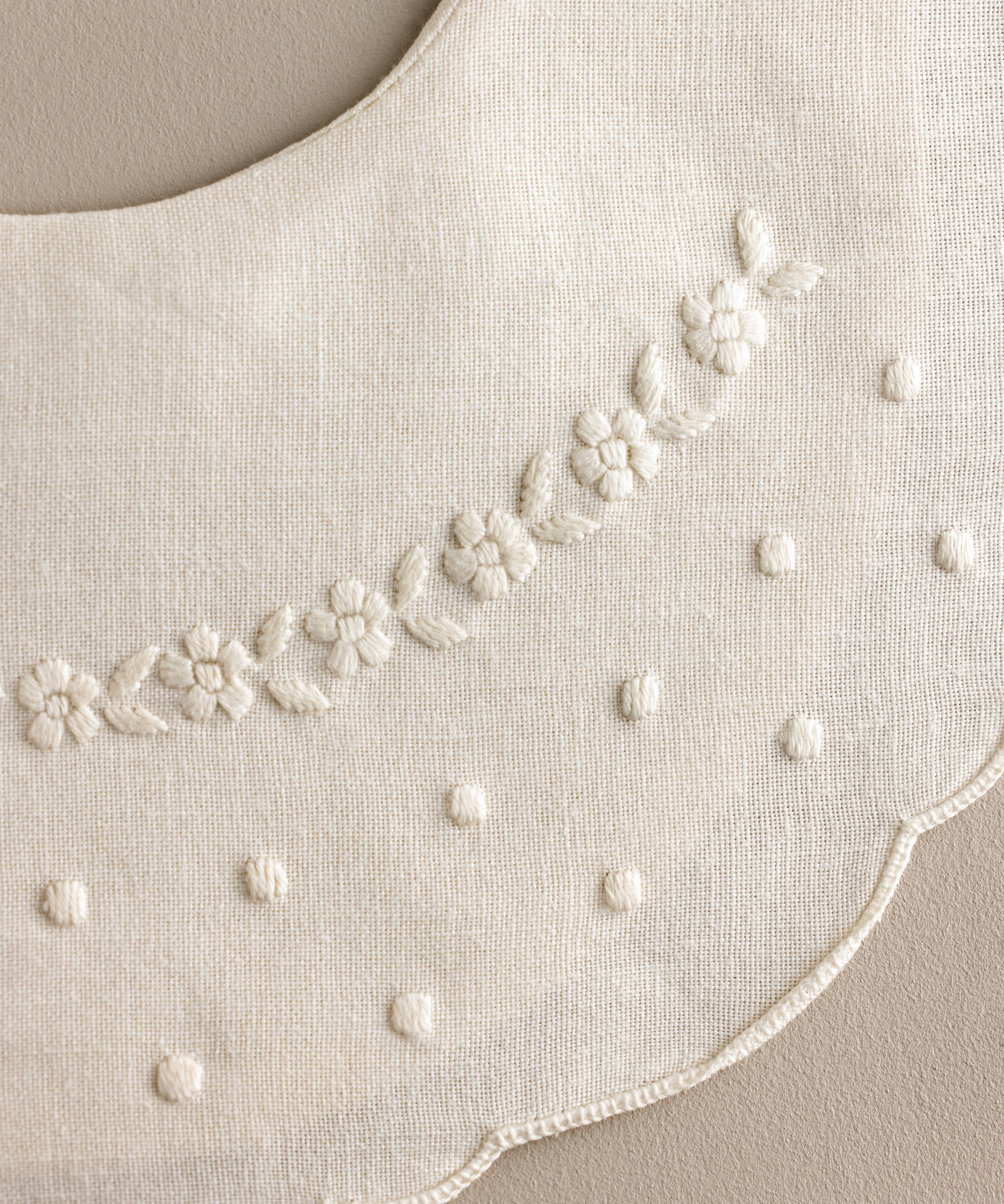 Detalle Babero bebé lino bordado flores blanco con bodoques.Ref.114E