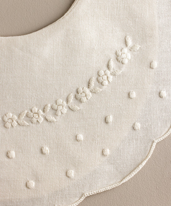 Detalle Babero bebé lino bordado flores blanco con bodoques.Ref.114E