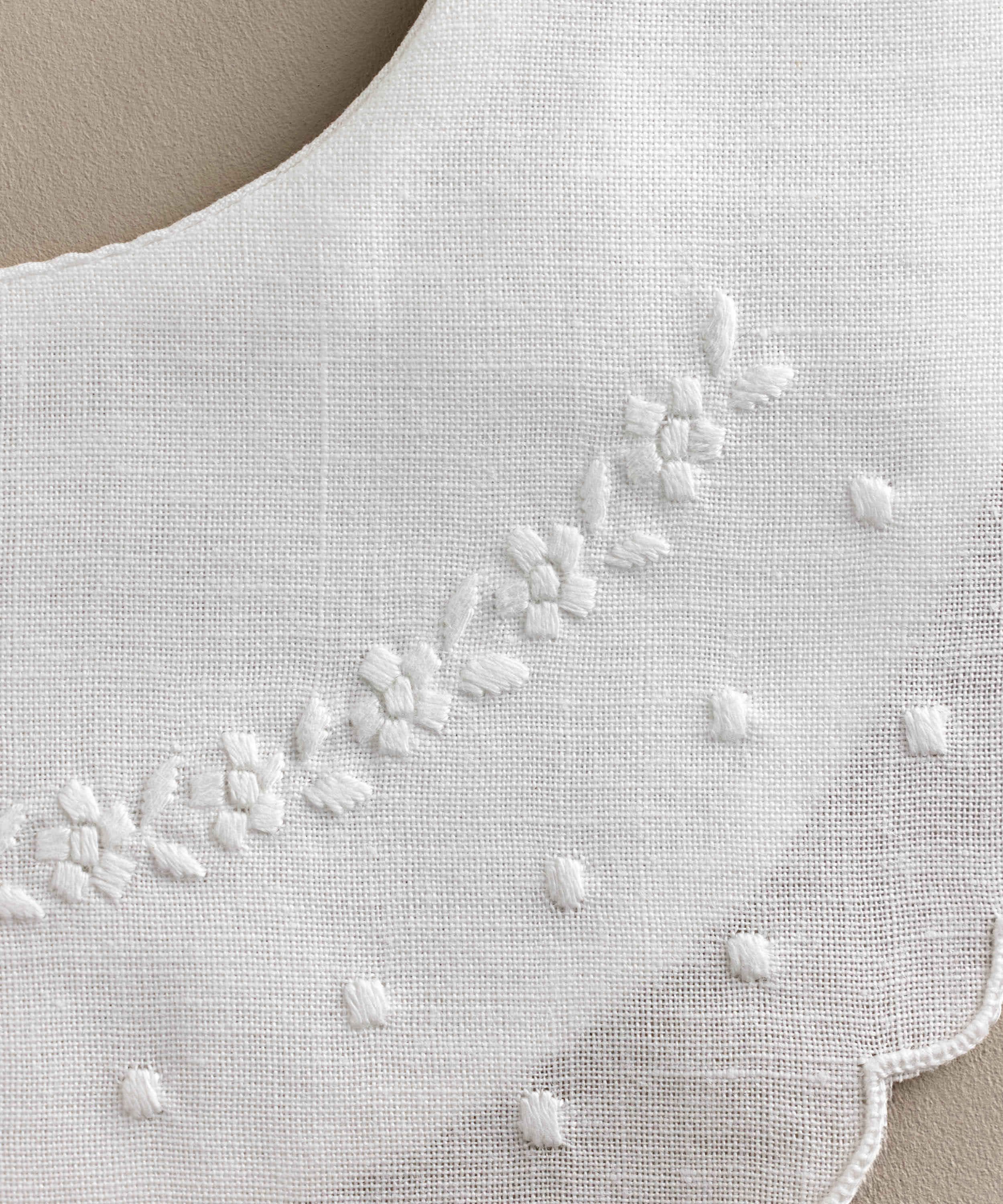 Detalle Babero bebé lino bordado flores y bodoques blanco.Ref.114W