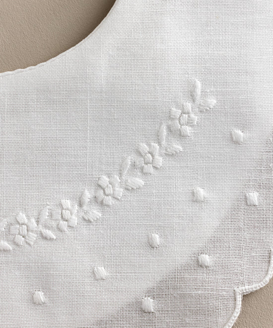 Detalle Babero bebé lino bordado flores y bodoques blanco.Ref.114W