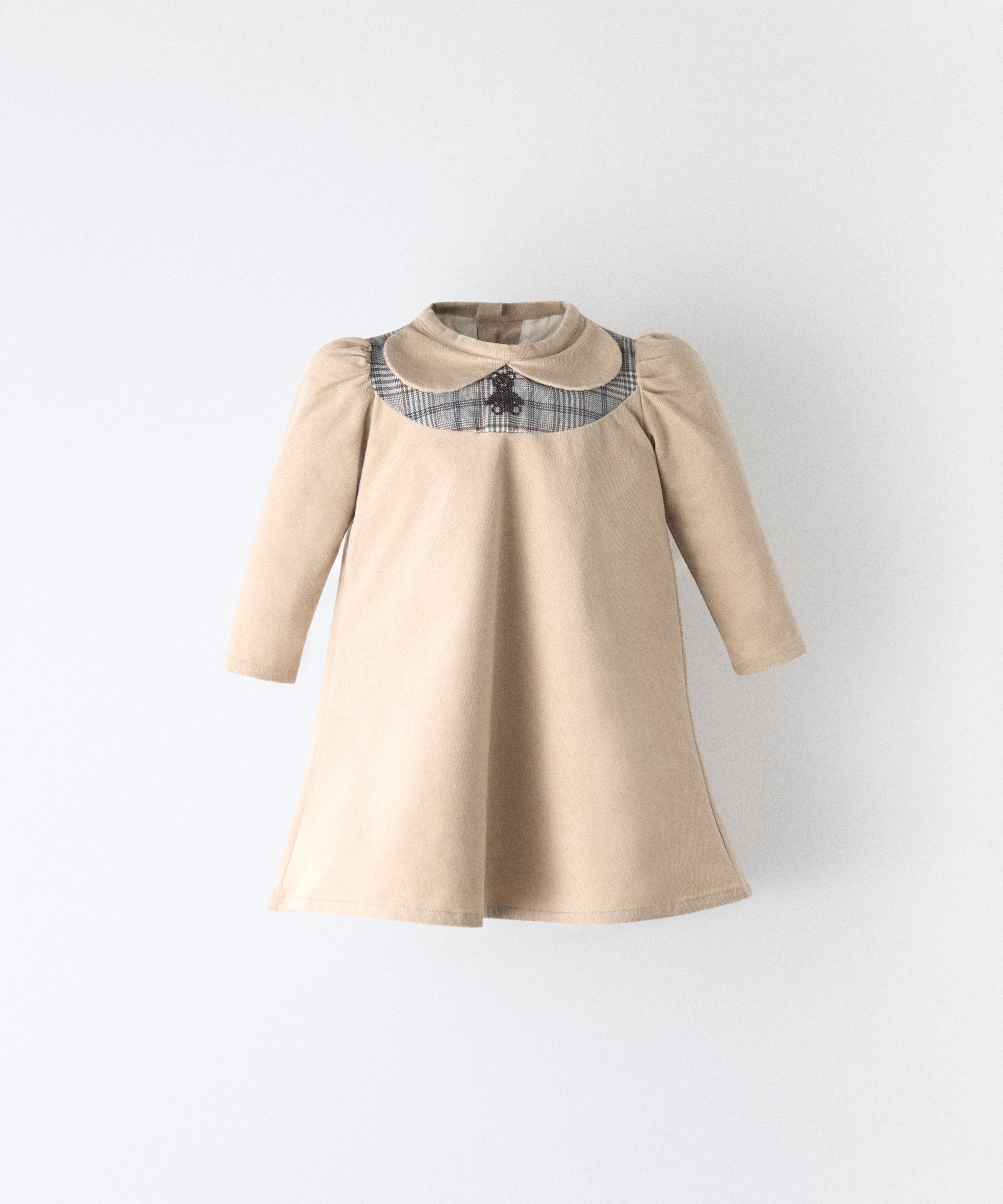 El Faldón Wills beige, confeccionado en pana elástica (97 % algodón BCI / 3 % elastano) con pieza delantera a cuadros y oso kala bordado. Una prenda que celebra los primeros momentos con autenticidad, sensibilidad y estilo atemporal.