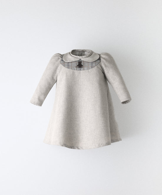 El Faldón Wills gris claro, confeccionado en sarga 100 % algodón BCI con pieza delantera a cuadros y oso kala bordado. Una prenda que celebra los primeros momentos con autenticidad, sensibilidad y estilo atemporal.