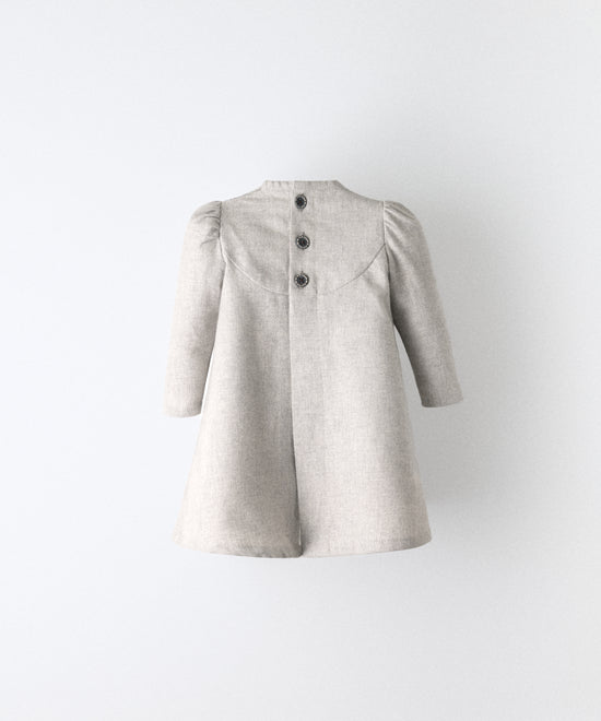 El Faldón Wills gris claro visto de espaldas, confeccionado en sarga 100 % algodón  y apertura total central con cierre con botones OEKO TEX en la parte superior. Una prenda que celebra los primeros momentos con autenticidad, sensibilidad y estilo atemporal.