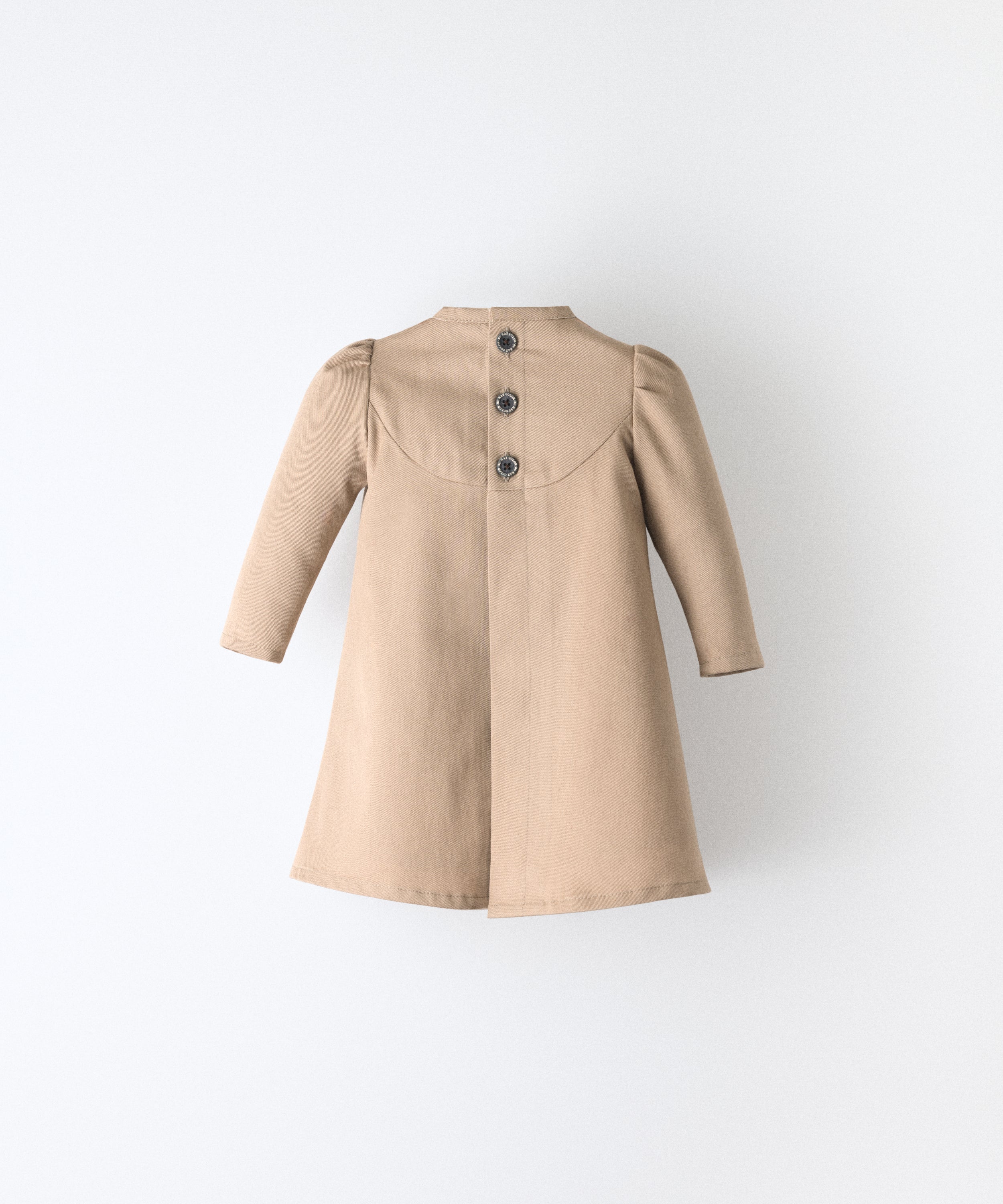 El Faldón Wills avellana visto de espaldas, confeccionado en sarga 100 % algodón orgánico certificado GOTS con apertura total central con cierre con botones OEKO TEX en la parte superior. Una prenda que celebra los primeros momentos con autenticidad, sensibilidad y estilo atemporal.