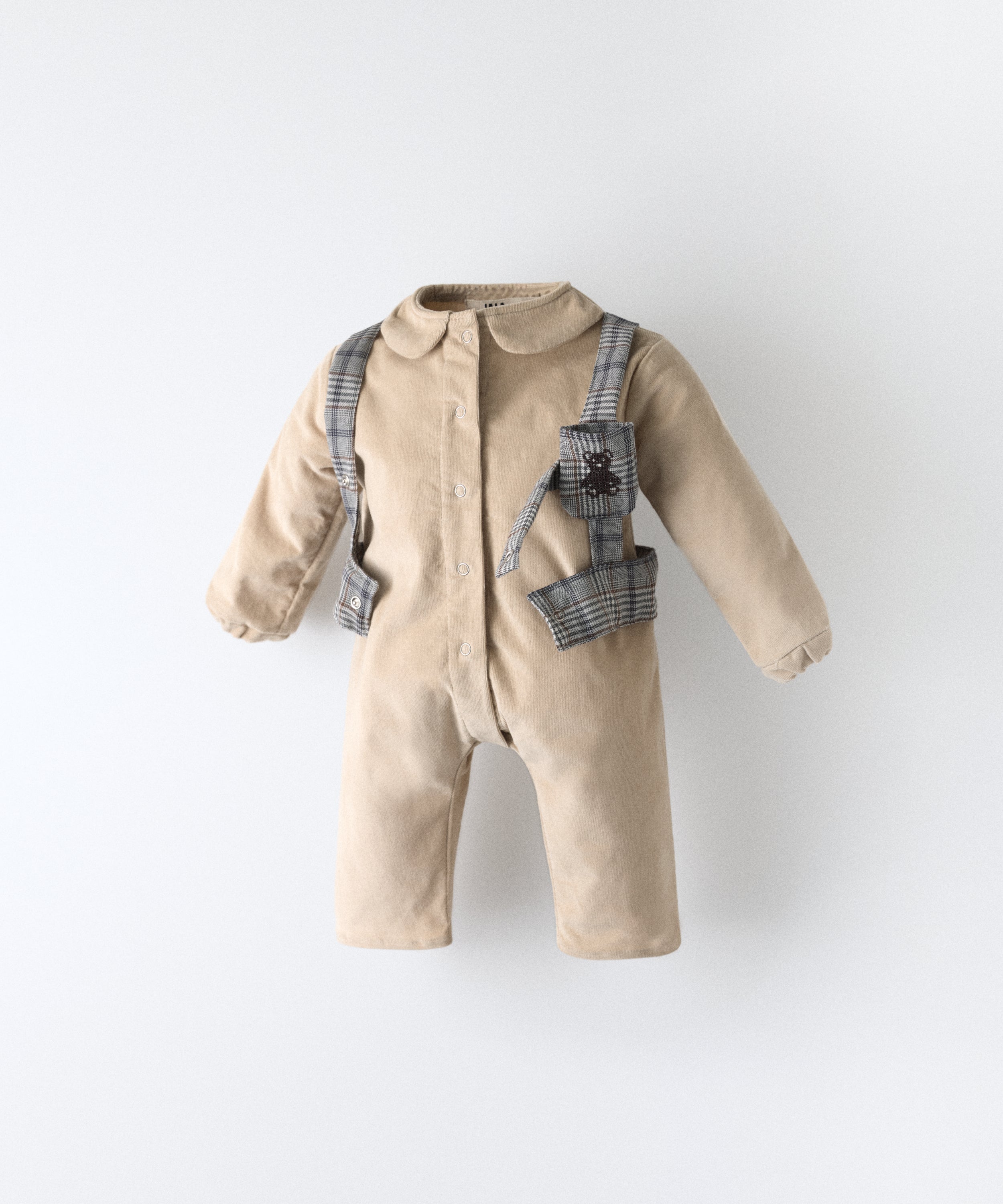 Jumpsuit bebé beige de pana BCI con arnés GRS abierto, cuello estructurado y logo bordado Kala.