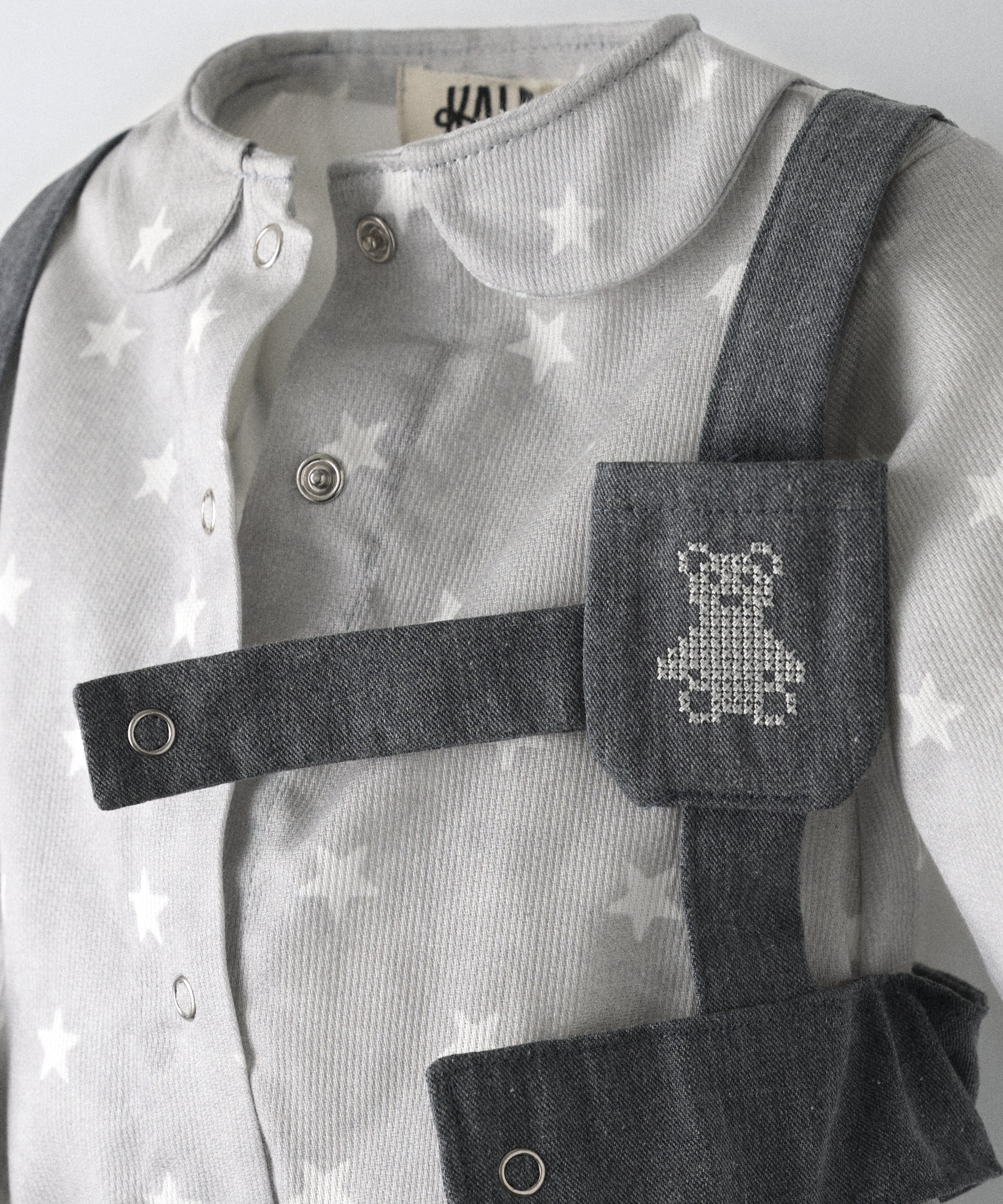 Detalle del arnés en denim GRS con bolsillo para chupete y logo bordado Kala.