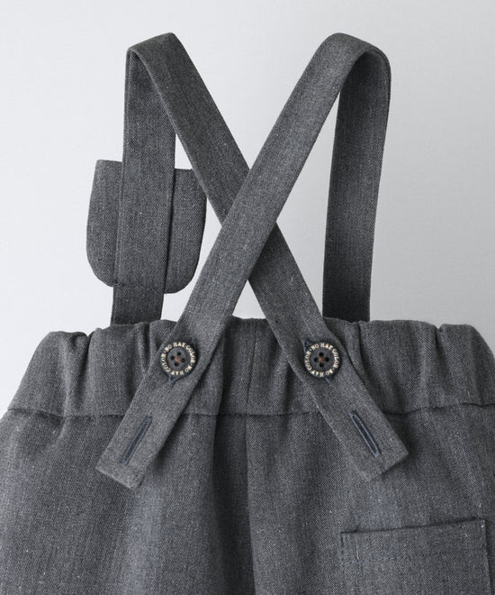 Vista trasera del pantalón bebé gris azulado con tirantes cruzados ajustables con botones oEKO TEX y cintura elástica.