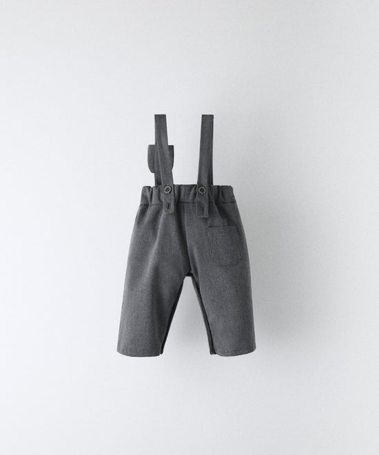 Vista trasera del pantalón bebé gris azulado con tirantes rectos y cintura elástica.