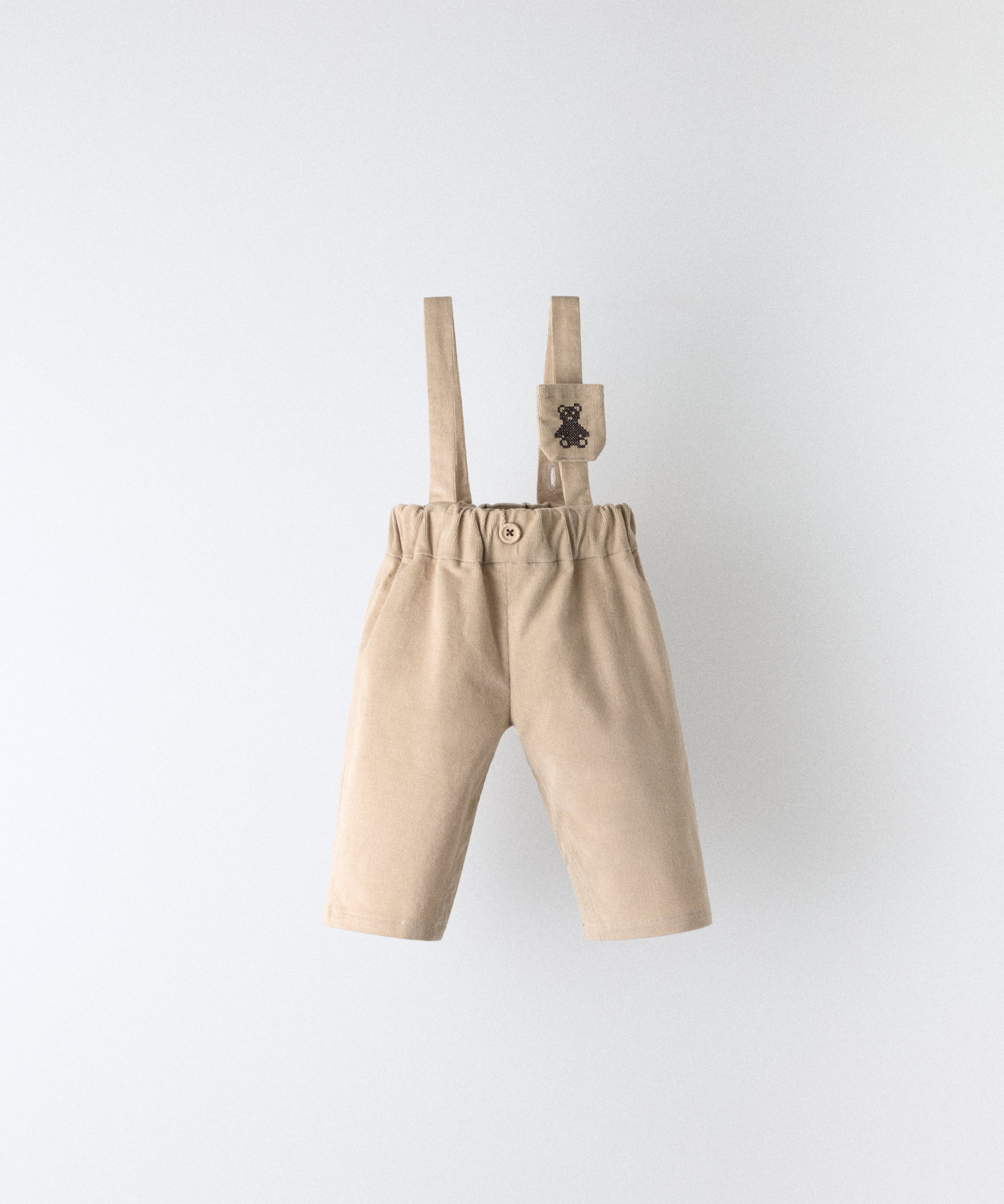 Pantalón bebé beige de pana elástica BCI con tirantes ajustables y bolsillo para chupete Kala.