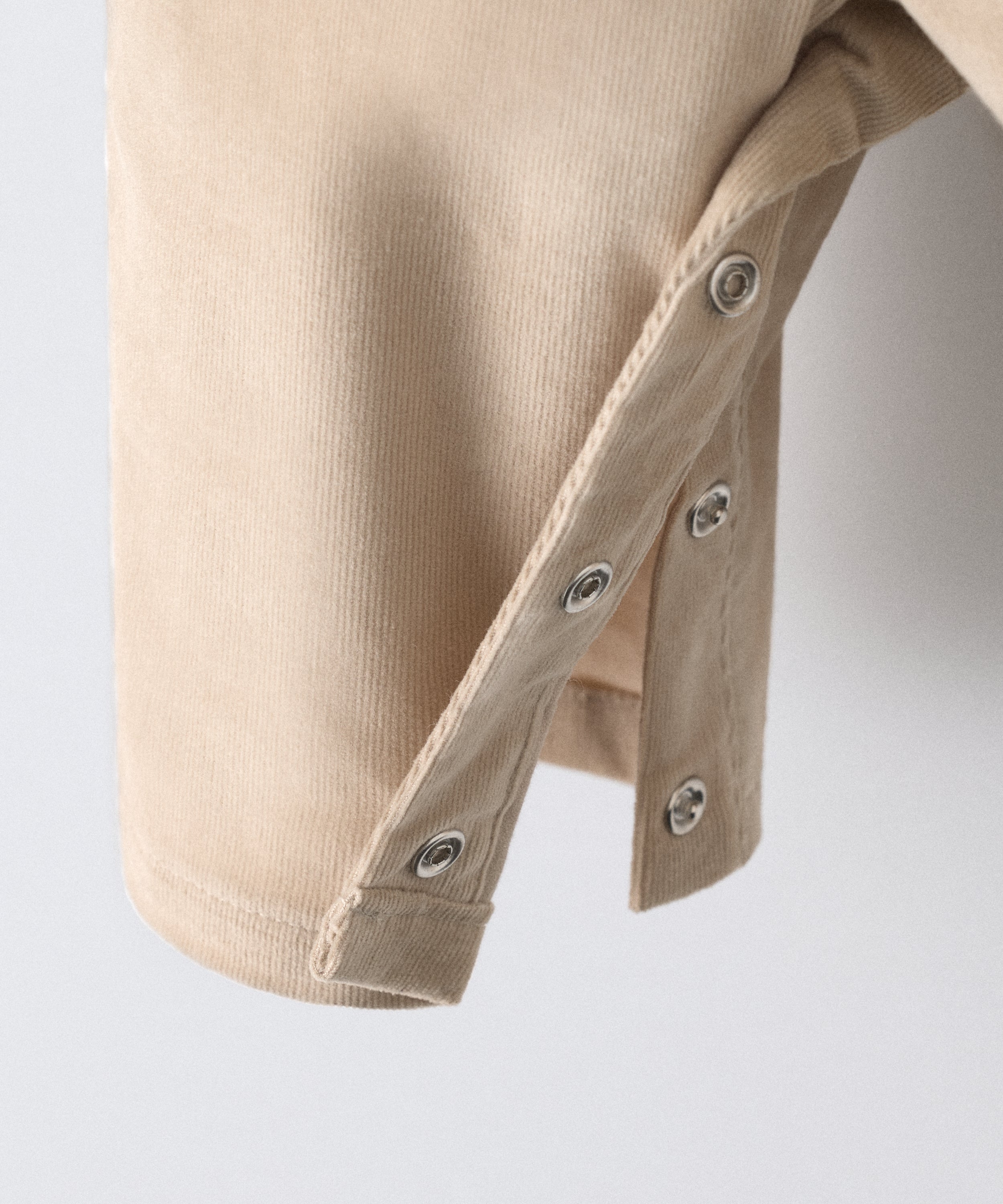 Textura de la pana elástica BCI beige y acabados artesanales del pantalón Kala.