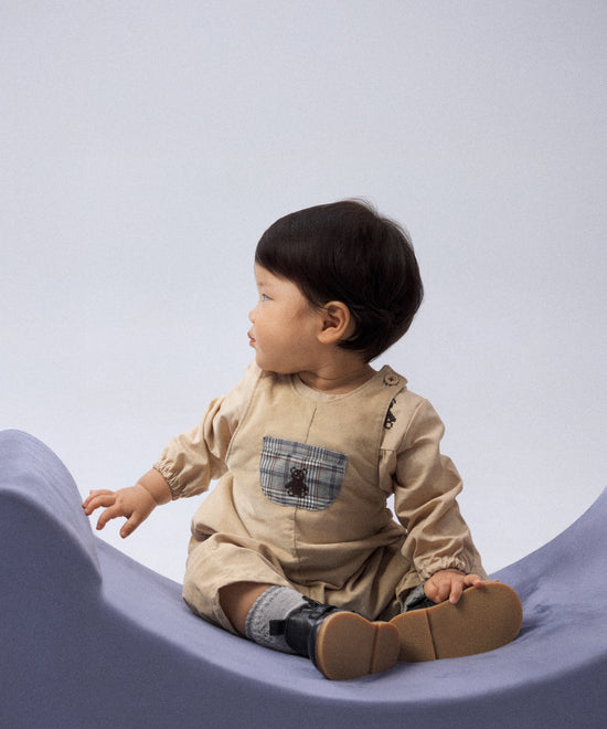 El Peto Land Baby beige Kala, diseño artesanal en pana elástica BCI para bebés de 0 a 24 meses.