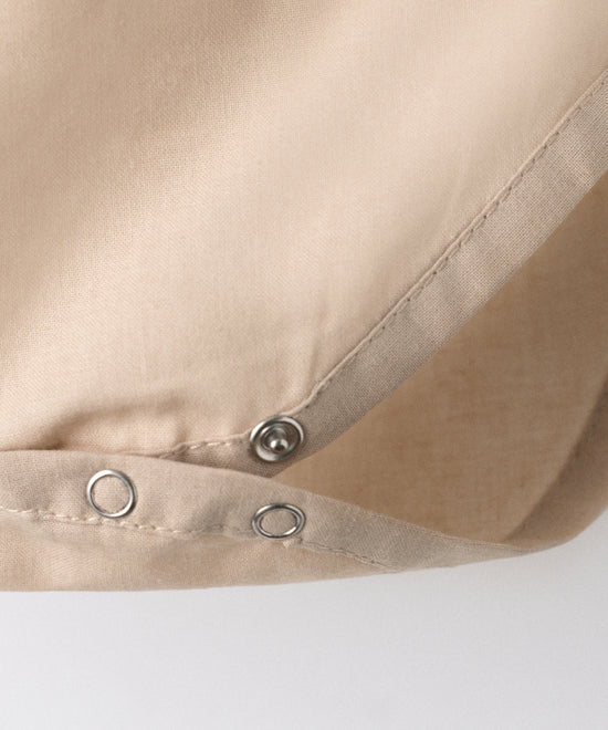 Detalle cierre automático en entrepierna del body Liberty color arena blanqueada. Confeccionado en 100 % algodón orgánico certificado GOTS. Suavidad y cuidado de la piel para tu bebé. www.kala.es