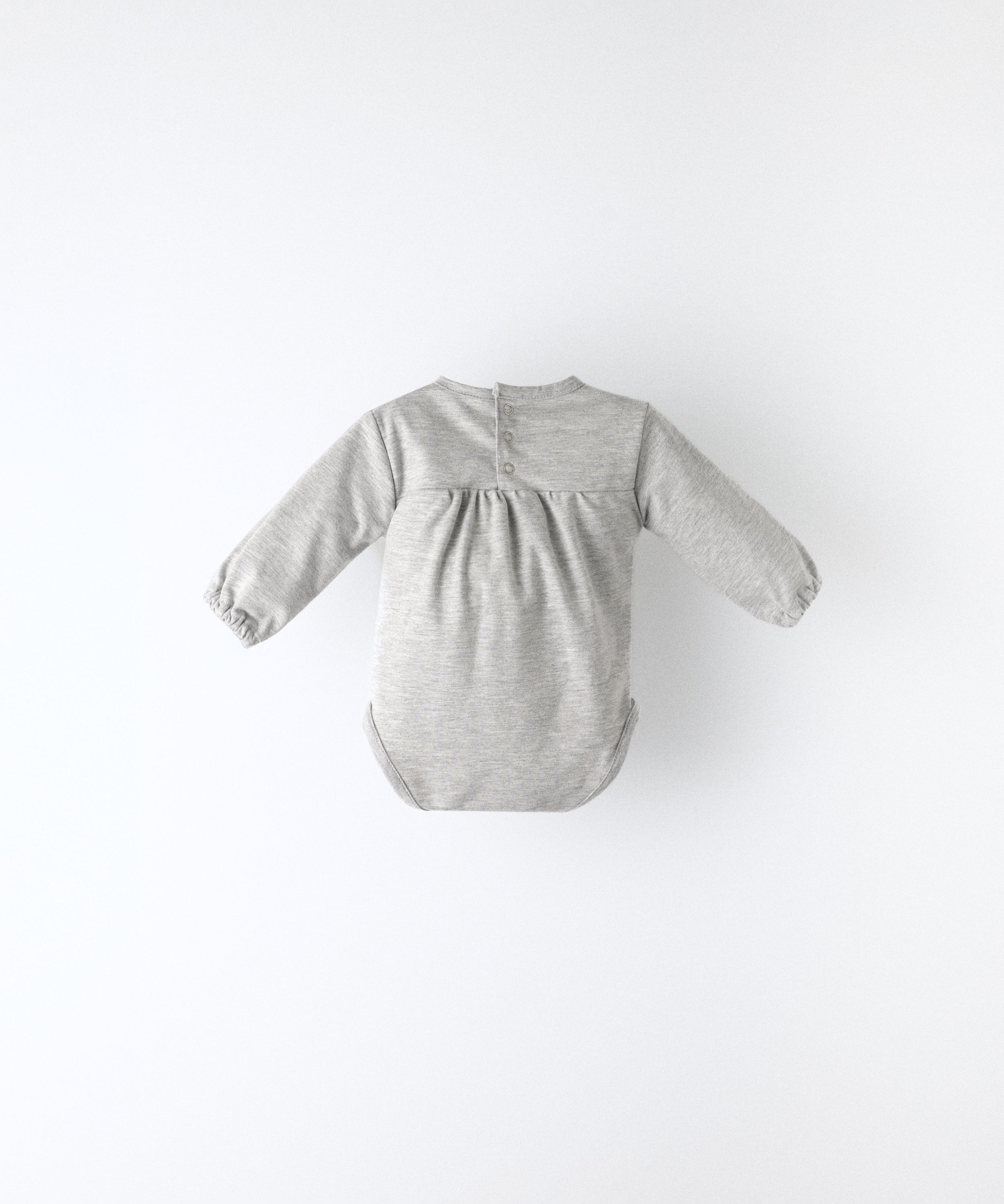 Espalda del Body Liberty en manga larga y color gris claro. Confeccionado en punto 97 % algodón orgánico + 3 % elastano, certificado GOTS. Suavidad y cuidado de la piel para tu bebé. www.kala.es