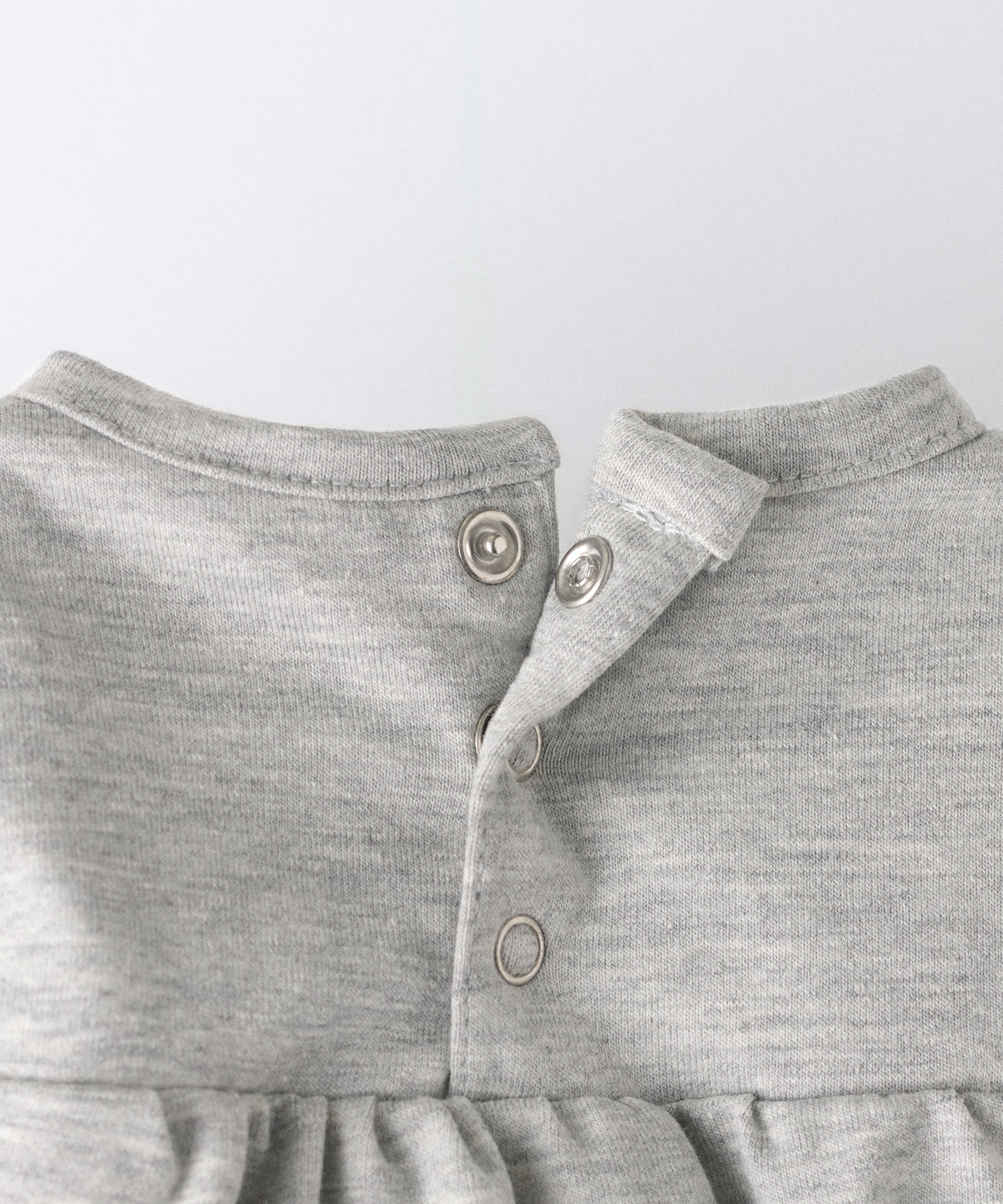 Detalle apertura espalda con cierre automáticos. Practicidad en el body Liberty en manga larga y color gris claro. Confeccionado en punto 97 % algodón orgánico + 3 % elastano, certificado GOTS. Suavidad y cuidado de la piel para tu bebé. www.kala.es