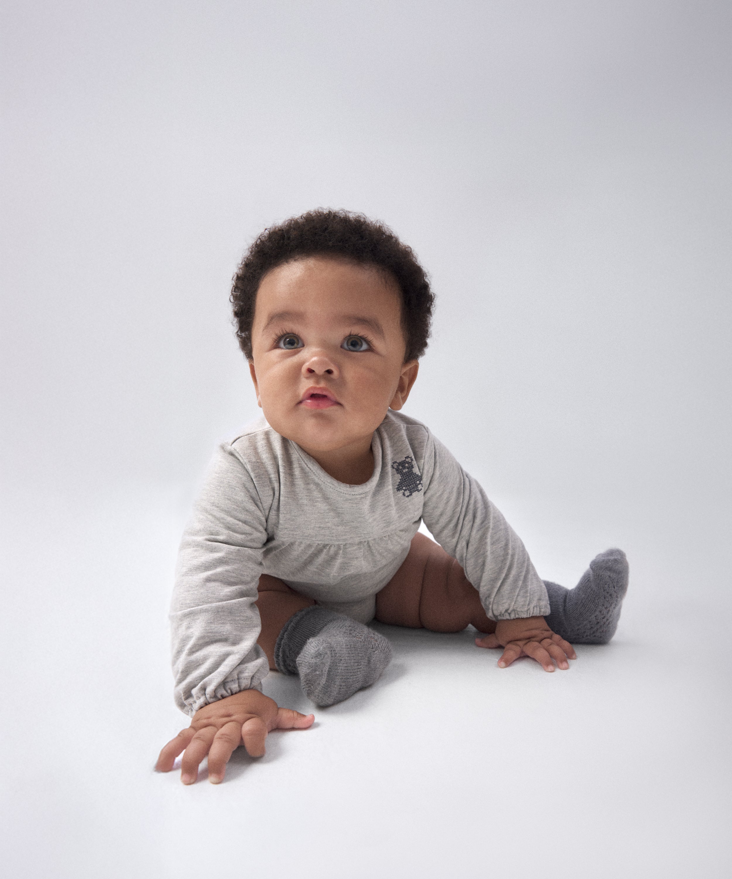 Modelo bebé con El Body Liberty Gris Claro. Confeccionado en punto 97 % algodón orgánico + 3 % elastano, certificado GOTS. Suavidad y cuidado de la piel para tu bebé. www.kala.es