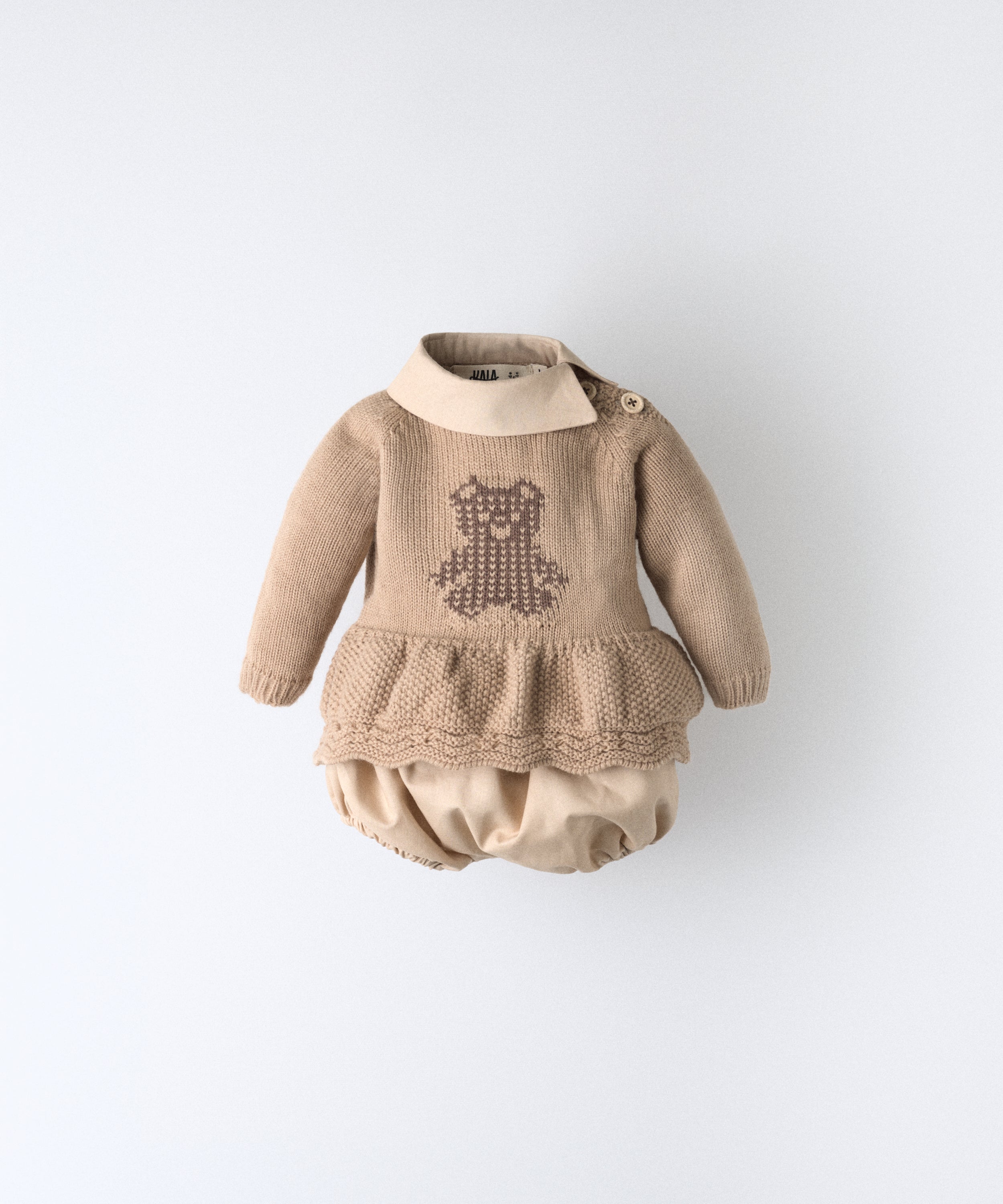 El Conjunto Bloomer color arena blanqueada con cuello y pantalón bloomer en este tono confeccionado en algodón orgánico certificado GOTS; forro del pantalón 100% algodón.
Vestido en punto acrílico con oso de Kala en intarsia marrón. www.kala.es