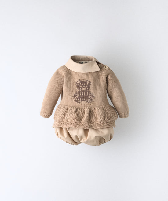 El Conjunto Bloomer color arena blanqueada con cuello y pantalón bloomer en este tono confeccionado en algodón orgánico certificado GOTS; forro del pantalón 100% algodón.
Vestido en punto acrílico con oso de Kala en intarsia marrón. www.kala.es