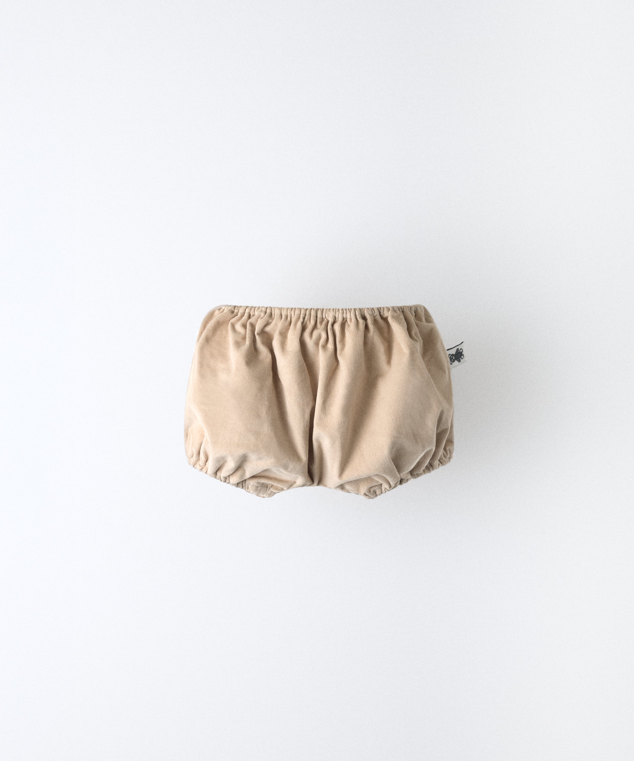 El Pantalón bloomer del conjunto confeccionado en pana beige de algodón BCI e interior en forro 100% algodón. Engomado superior e inferiores. Máximo confort para tu bebé. www.kala.es