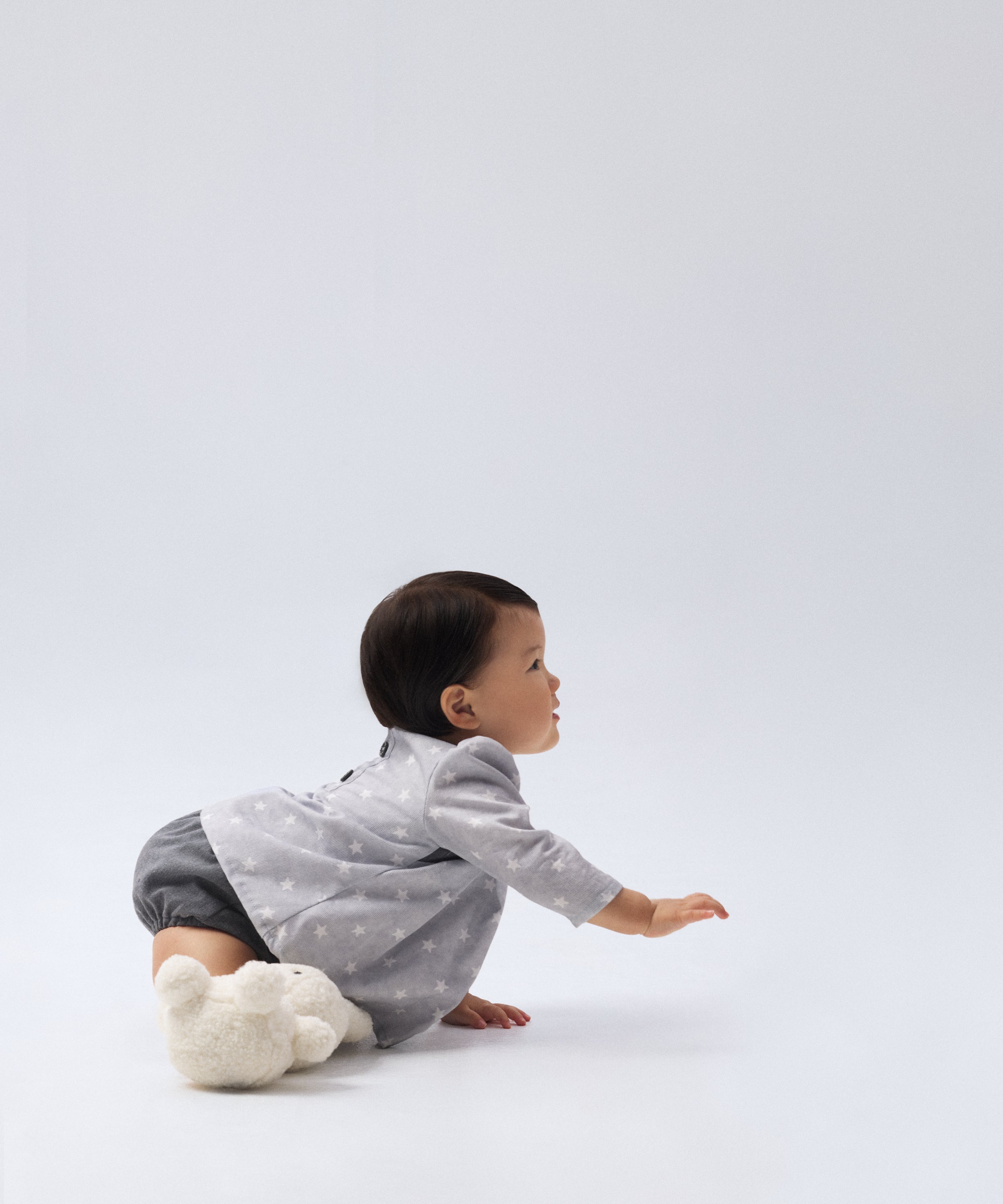 Modelo bebé vestida con El Conjunto Harper en tejido estampado de estrellas y cubrepañal en sarga premium denim gris azulado PL reciclado GRS; forro 100 % algodón. Elegancia y diseño para tu bebé. www.kala.es