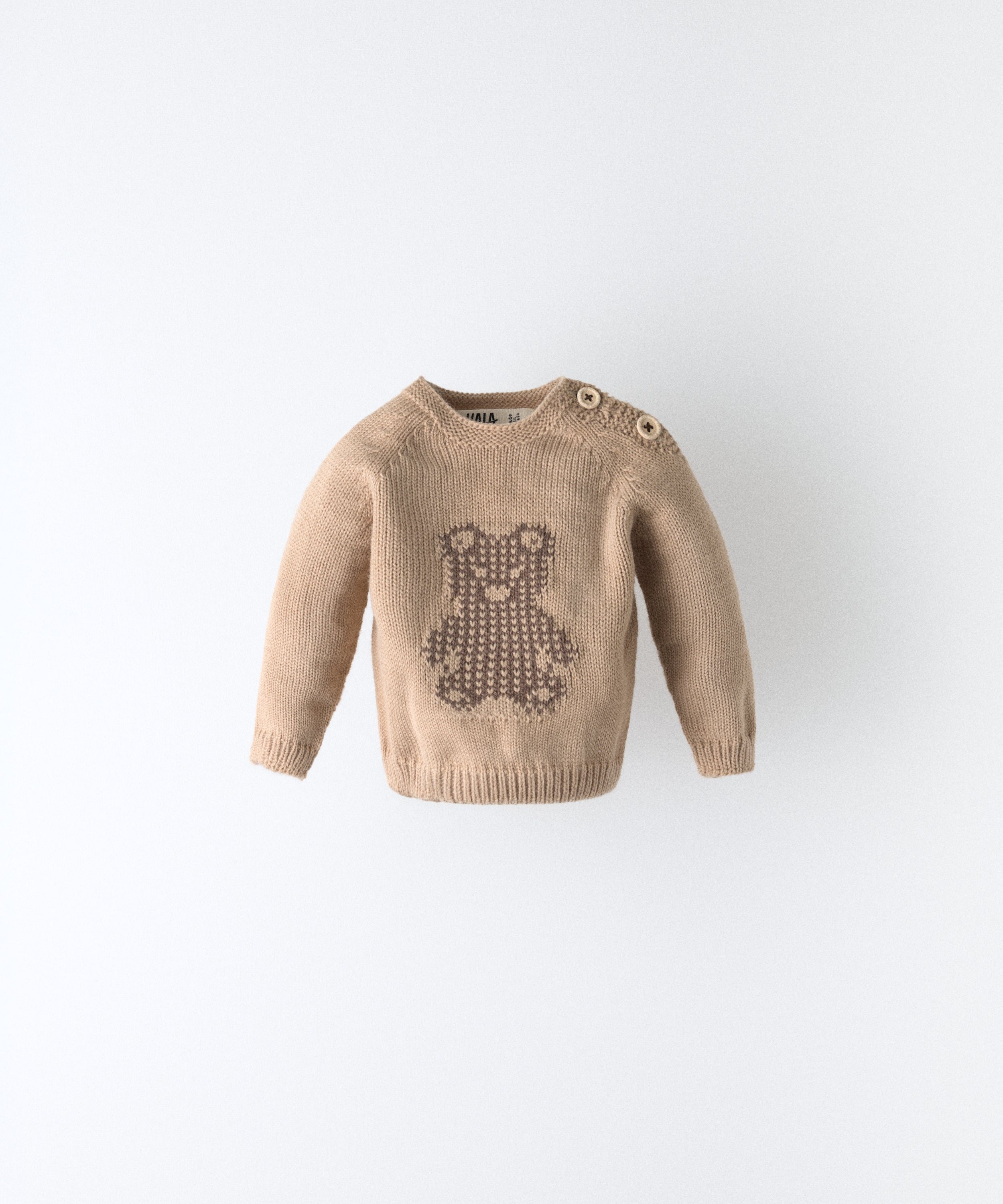 Delantero del Jersey beige del Conjunto Strutt.  Diseño con oso Kala en intarsia marrón y abertura en hombro con cierre botones OEKO TEX al tono. Engomado en puños y cintura. Diseño único para tu bebé. www.kala.es