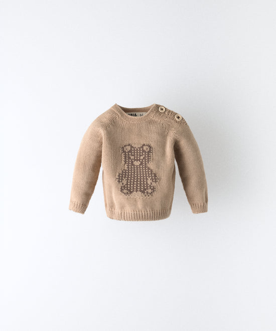 Delantero del Jersey beige del Conjunto Strutt.  Diseño con oso Kala en intarsia marrón y abertura en hombro con cierre botones OEKO TEX al tono. Engomado en puños y cintura. Diseño único para tu bebé. www.kala.es