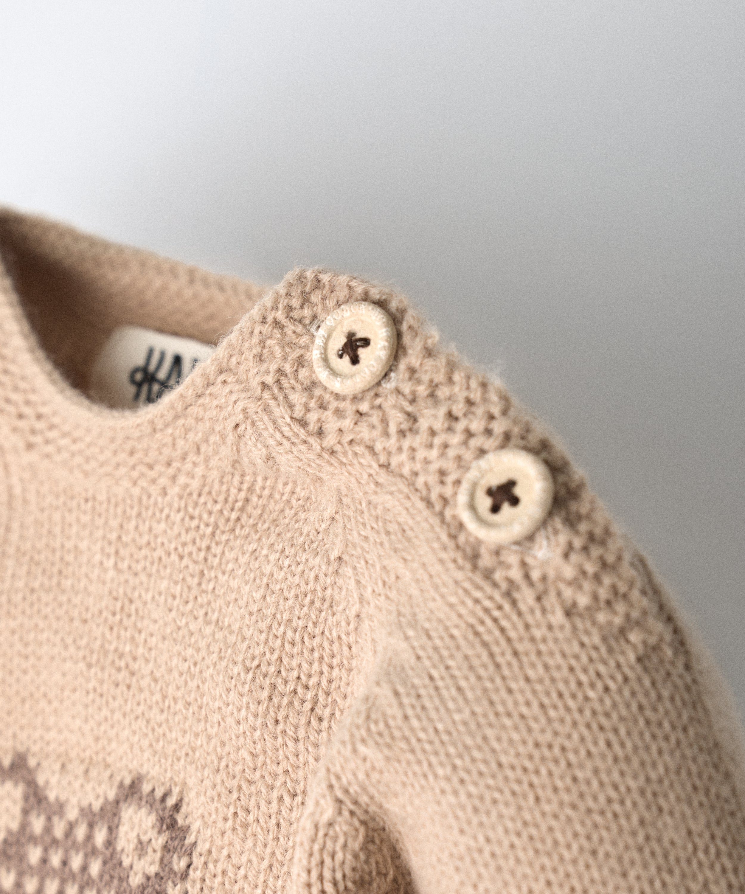 Detalle de abertura y cierre en hombro del jersey del Conjunto Strutt beige. Botones OEKO TEX al tono. Facilidad para vestir a los más pequeños. www.kala.es