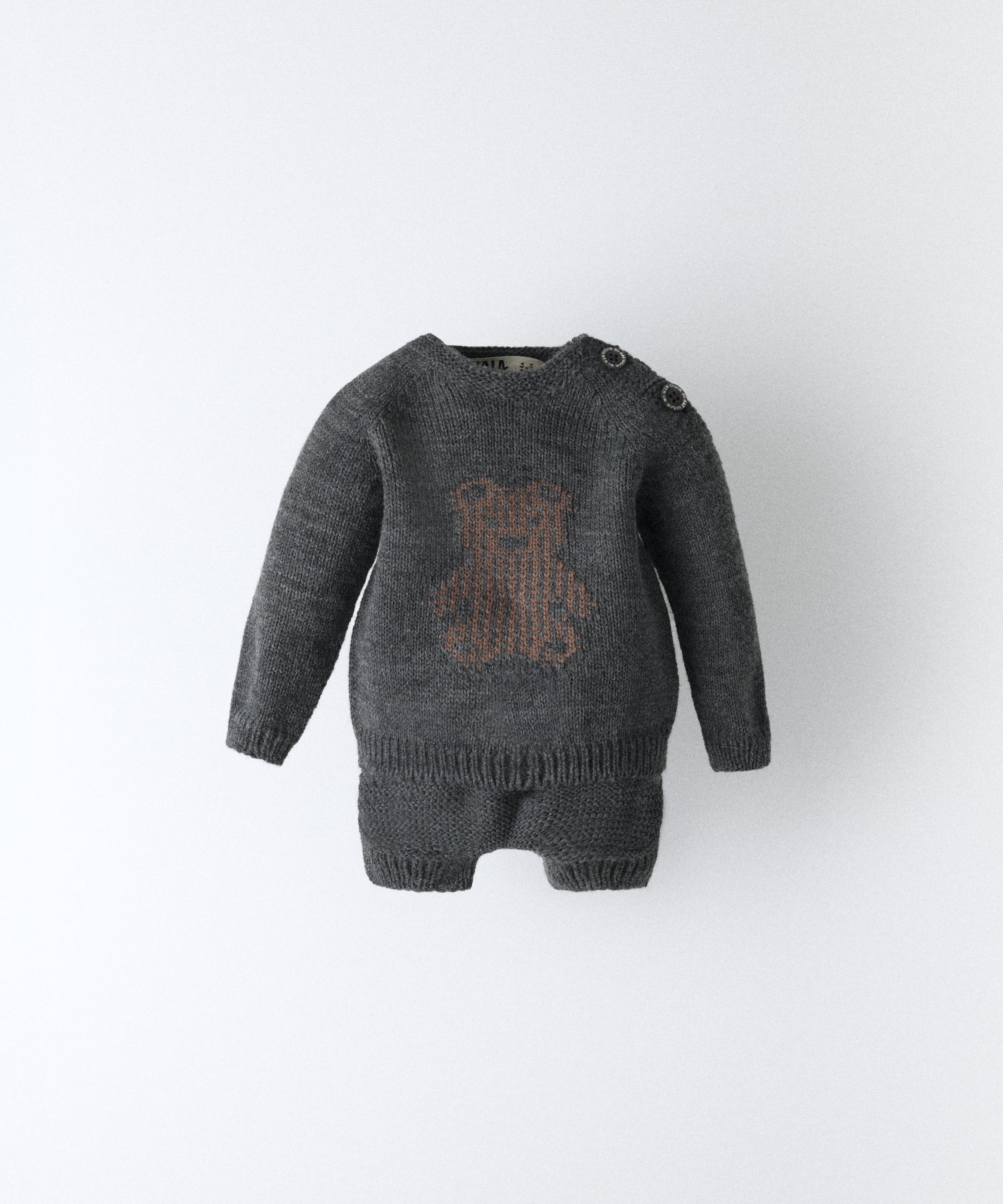 El Conjunto Strutt gris oscuro de Kala está compuesto por dos piezas, un pantalón corto y un jersey de manga larga con oso marrón en intarsia. Una fórmula que eleva lo cotidiano desde los primeros pasos. www.kala.es