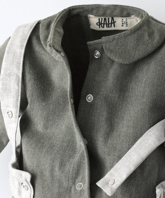 Detalle de cierre delantero con botos automáticos del Jumpsuit Snook verde khaki con arnés abierto. Diseño y atemporalidad para tu bebé. Pensado para acompañar el crecimiento con comodidad y carácter. www.kala.es