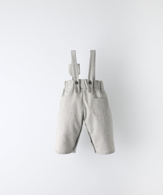 Vista trasera del Pantalón Miller gris claro confeccionado con 100 % algodón BCI. Tirantes ajustables con botón OEKO TEX al contraste. Diseño y versatilidad para tu bebé. www.kala.es