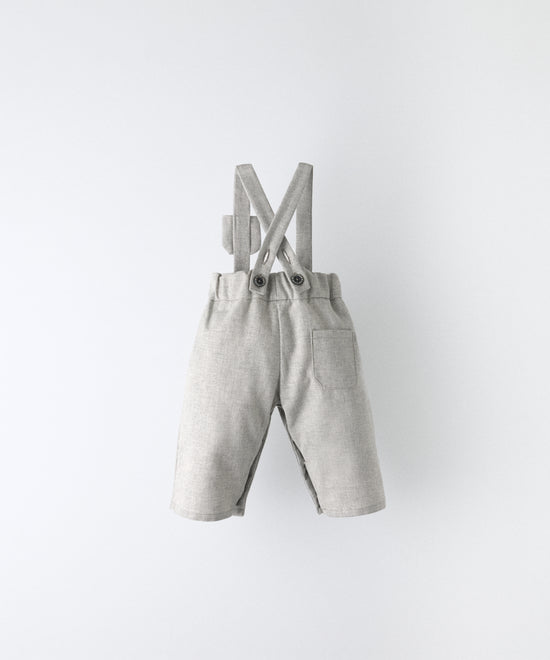 Vista trasera del Pantalón Miller gris claro confeccionado con 100 % algodón BCI. Tirantes cruzados y ajustados con botón OEKO TEX al contraste. Diseño y versatilidad para tu bebé. www.kala.es