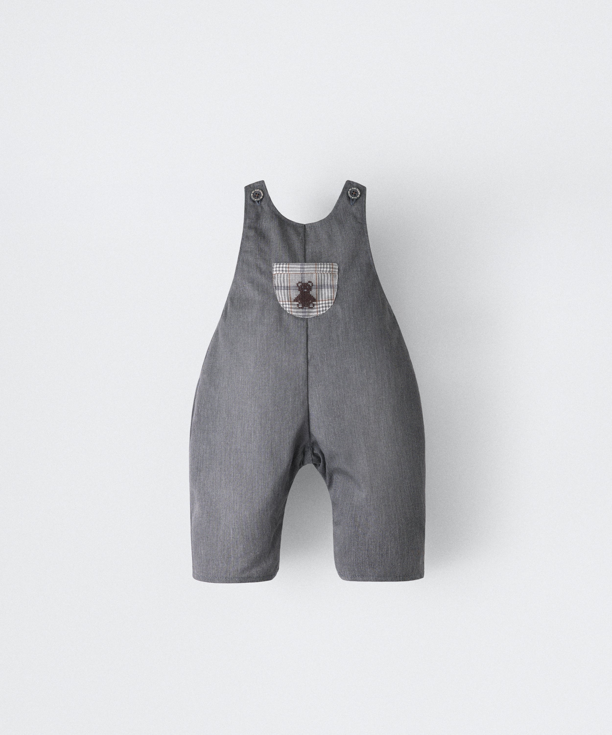 El Peto Land Baby en color gris azulado con tirantes con botones OEKO TEX. Confeccionado en sarga denim premium certificada GRS (Global Recycled Standard) y forro interior de 100 % algodón. Diseño efecto globo para la comodidad de tu bebé con bolsillo central al contraste a cuadros con oso Kala bordado en marrón. www.kala.es