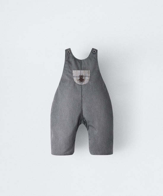 El Peto Land Baby en color gris azulado con tirantes con botones OEKO TEX. Confeccionado en sarga denim premium certificada GRS (Global Recycled Standard) y forro interior de 100 % algodón. Diseño efecto globo para la comodidad de tu bebé con bolsillo central al contraste a cuadros con oso Kala bordado en marrón. www.kala.es