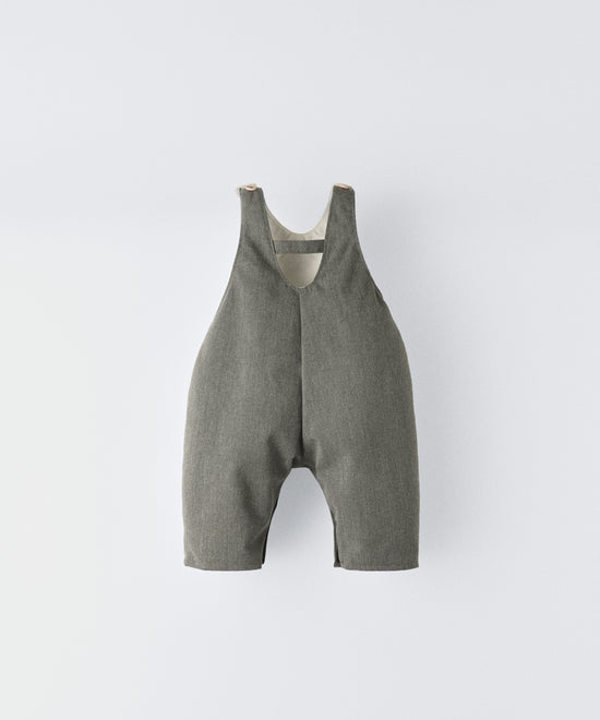 Espalda del Peto Land Baby en color verde Khaki con tirantes con botones OEKO TEX. Confeccionado en sarga denim premium certificada GRS (Global Recycled Standard) y forro interior de 100 % algodón. Diseño efecto globo para la comodiddad de tu bebé con bolsillo central con oso Kala bordado en beige. www.kala.es