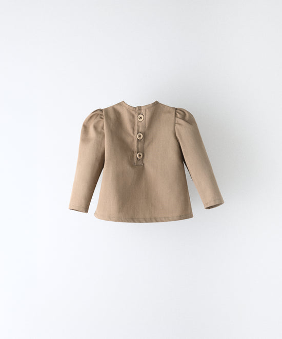Espalda del blusón avellana que forma parte del conjunto Harper. Espalda con apertura y cierre con botones OEKO TEX. Mangas largas con volumen en hombro. Delicadeza y estética para los más pequeños. www.kala.es
