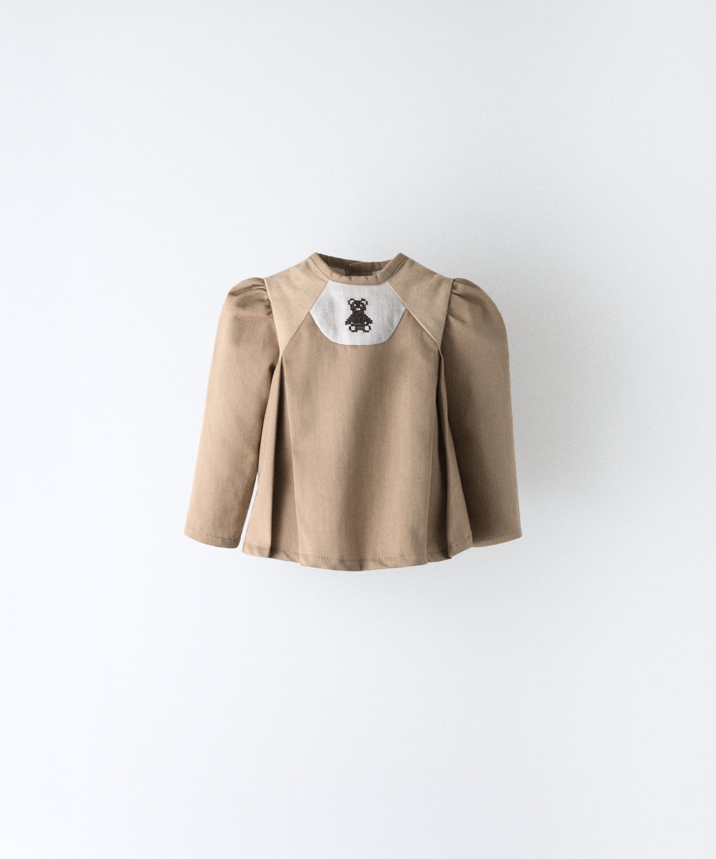 Delantero del blusón avellana con toques pana beige que forma parte del Conjunto Harper. Manga larga asentada con volumen en hombro y oso Kala bordado al contraste. Sin querer tu bebé será el centro de las miradas. www.kala.es