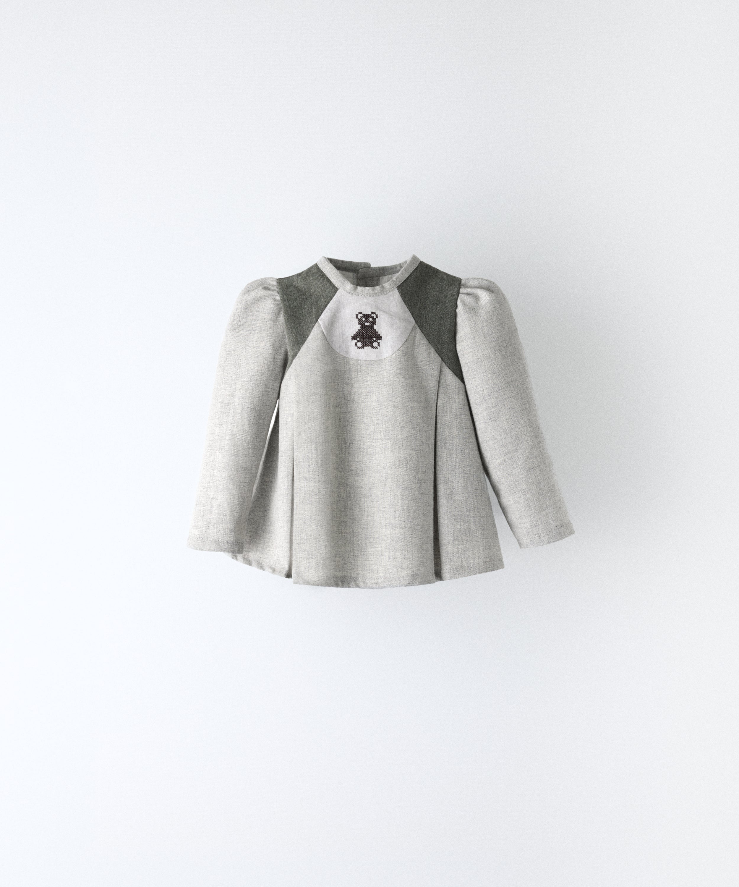 Delantero del blusón gris claro con toques verde khaki que forma parte del Conjunto Harper. Manga larga asentada con volumen en hombro y oso Kala bordado al contraste. Sin querer tu bebé será el centro de las miradas. www.kala.es