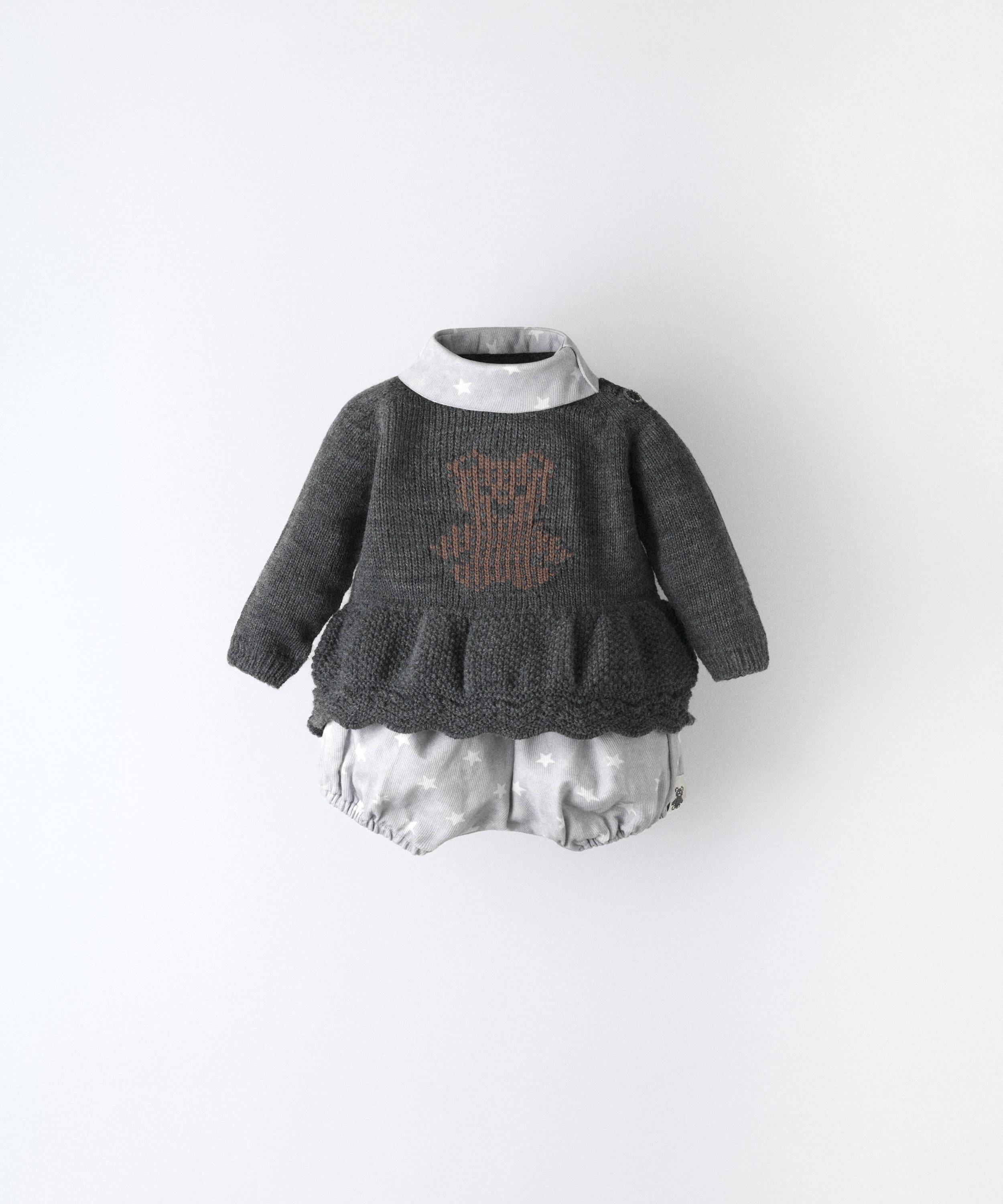 El Conjunto Bloomer, ideal para tu bebé, consta de un vestido de punto con oso de kala en intarsia marrón y cuello contrastado en sarga de piqué con estampado de estrellas blancas con fondo gris bebé. Y pantalón bloomer con engomados inferiores y superiores. Ideal para que tu bebé tenga un estilo único. www.kala.es