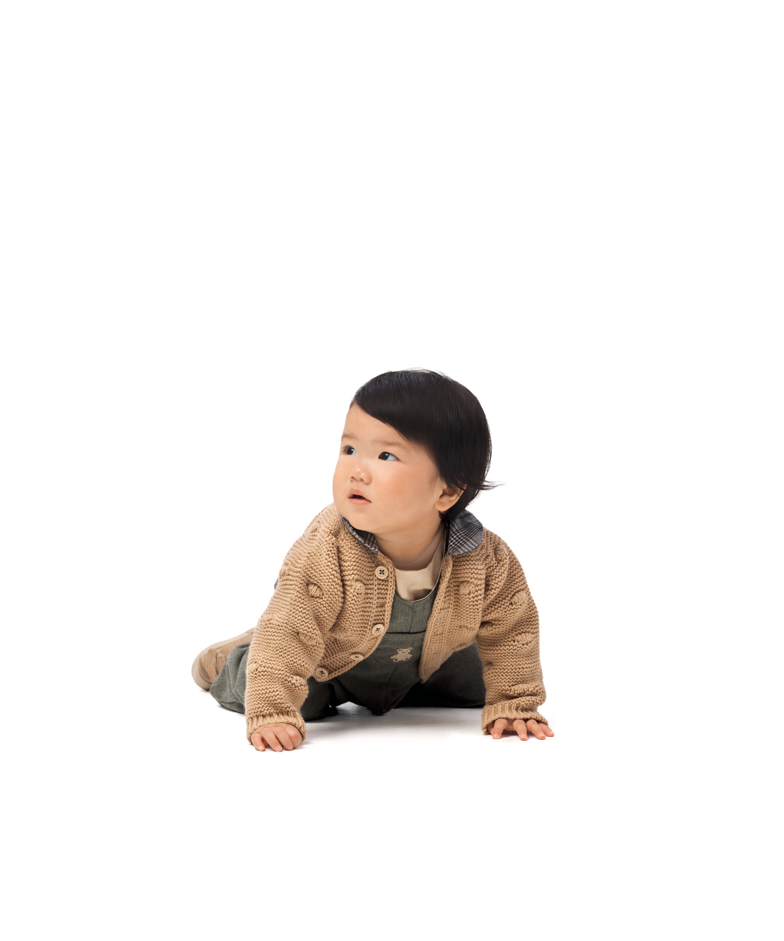 Look de ropa infantil de bebé de Kala. La bebé lleva puesto el pantalón el Peto Land Baby de tejido de sarga denim color verde khaki, la chaqueta Brunel en color beige y el body liberty en color beige. Diseño, sofisticación, elegancia y atemporalidad para la infancia. 