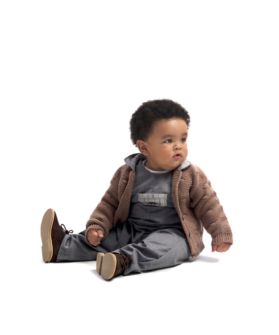 Look de ropa infantil de bebé de Kala. El bebé lleva puesto el Body Liberty en color gris claro, el Peto Land Baby en azul grisáceo y la chaqueta Brunel color marrón y cuello en contraste en tejido de cuadros. Sofisticación, elegancia y atemporalidad para la infancia. 