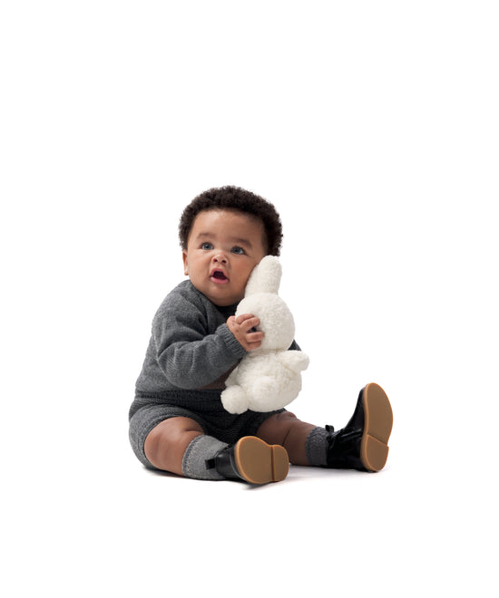 Look de ropa infantil de bebé de Kala. El bebé lleva puesto El conjunto Strutt de punto en color gris oscuro. Compuesto por jersey con oso de Kala en intarsia color marrón y pantalón. Sofisticación y elegancia para la infancia. 