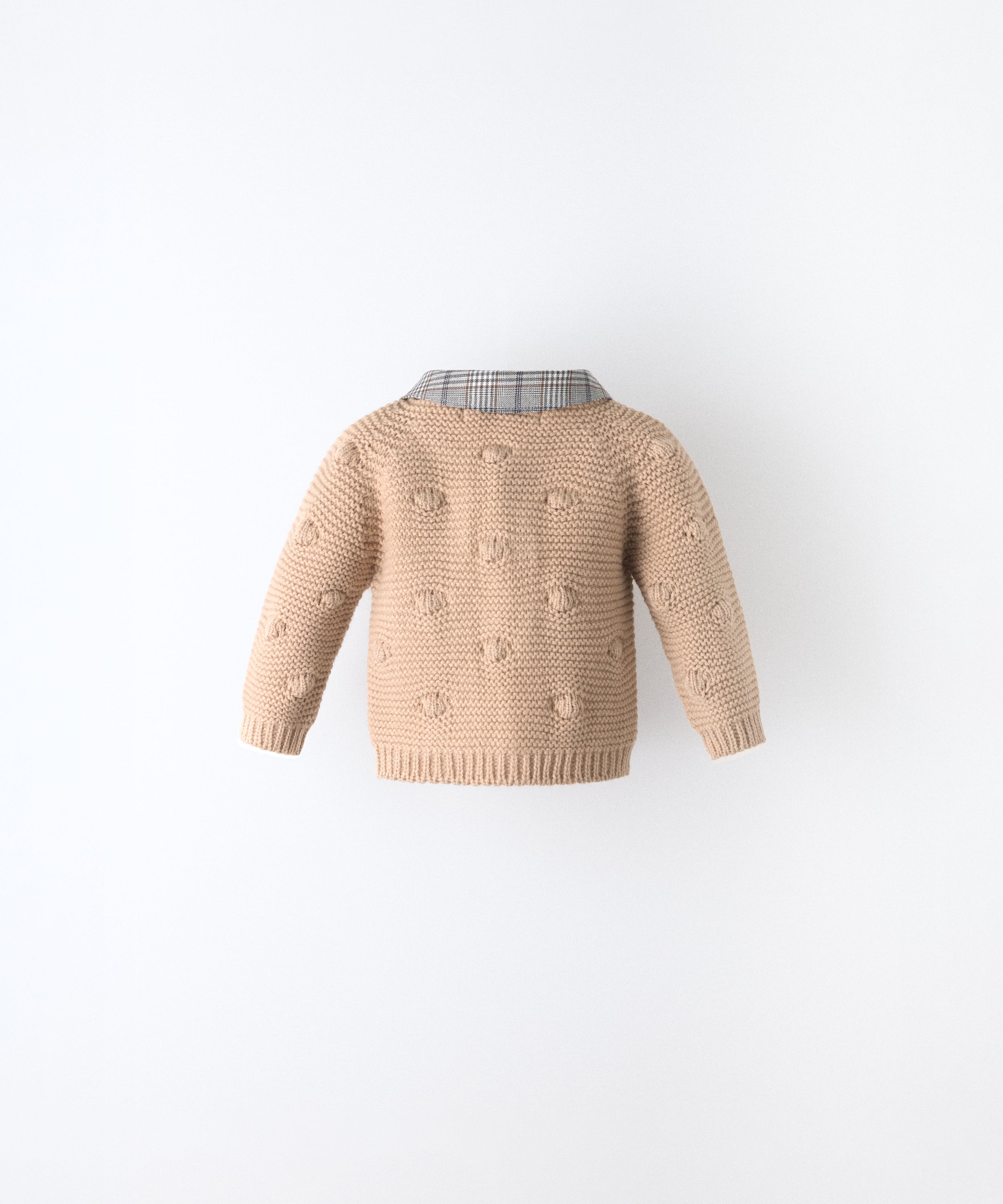 Espalda de La Chaqueta Brunel beige para bebé  en punto acrílico. Textura de bodoques y cuello contrastado en tejido de cuadros con certificación GRS. www.kala.es