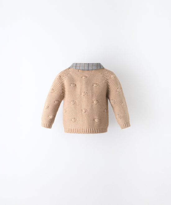 Espalda de La Chaqueta Brunel beige para bebé  en punto acrílico. Textura de bodoques y cuello contrastado en tejido de cuadros con certificación GRS. www.kala.es