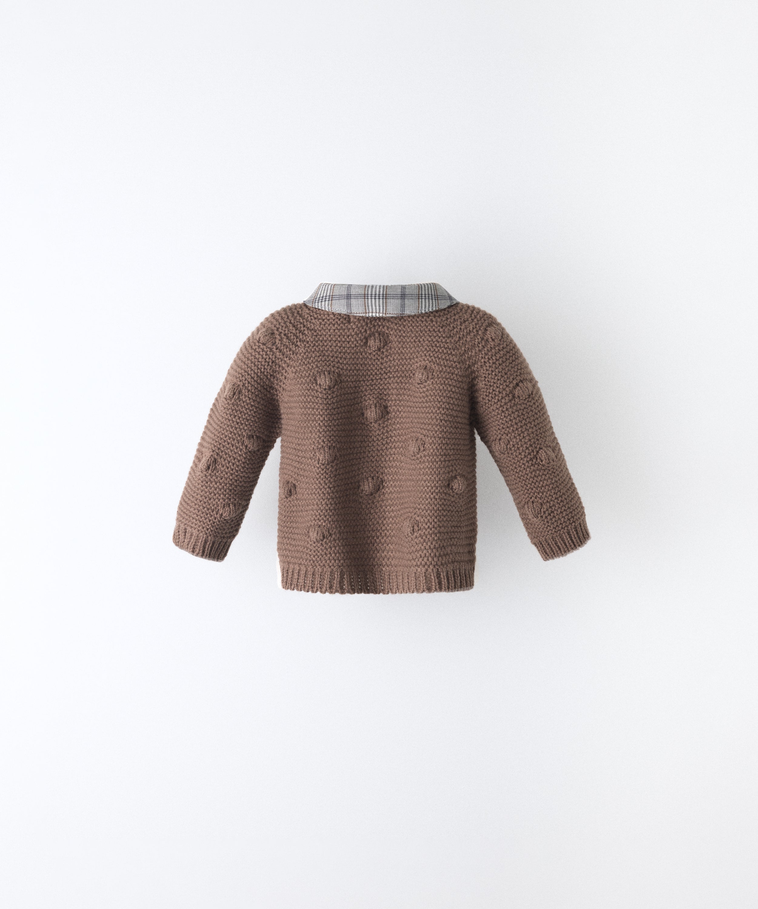 Espalda de La Chaqueta Brunel marrón para bebé  en punto acrílico. Textura de bodoques y cuello contrastado en tejido de cuadros con certificación GRS. www.kala.es