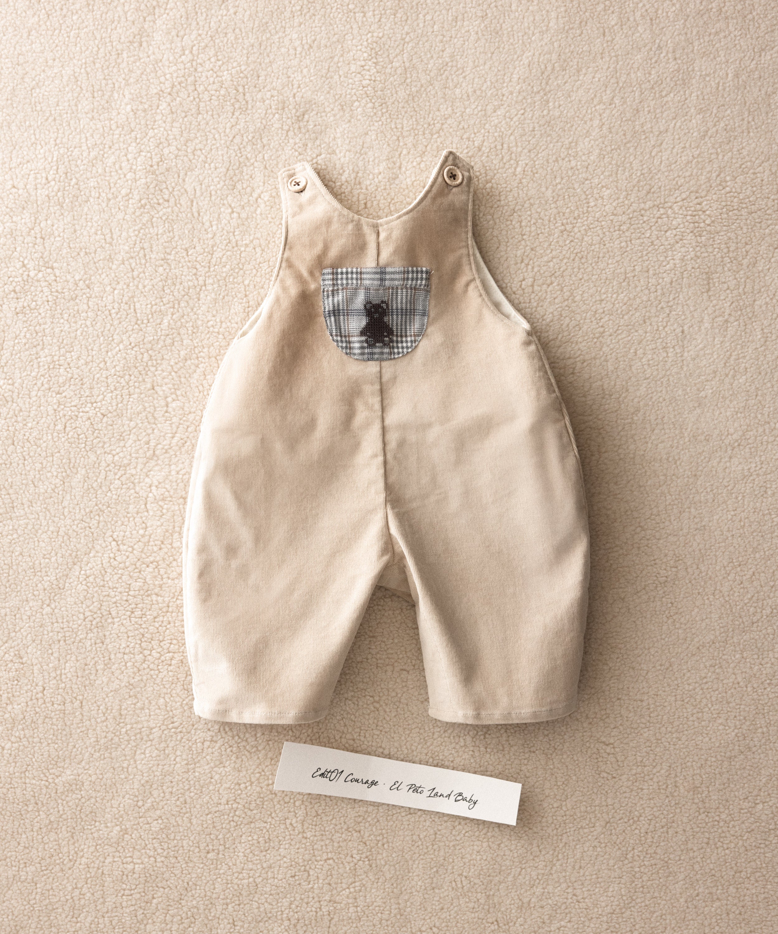 El peto de micropana color beige con silueta globo sobre un fondo con textura..