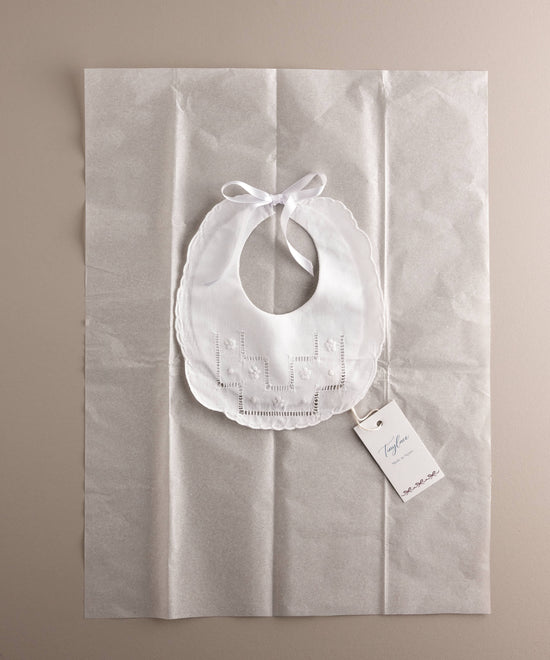 Babero recién nacido algodón bordado flor sobre papel seda y etiqueta de Tinylace emulando packaging.jpg