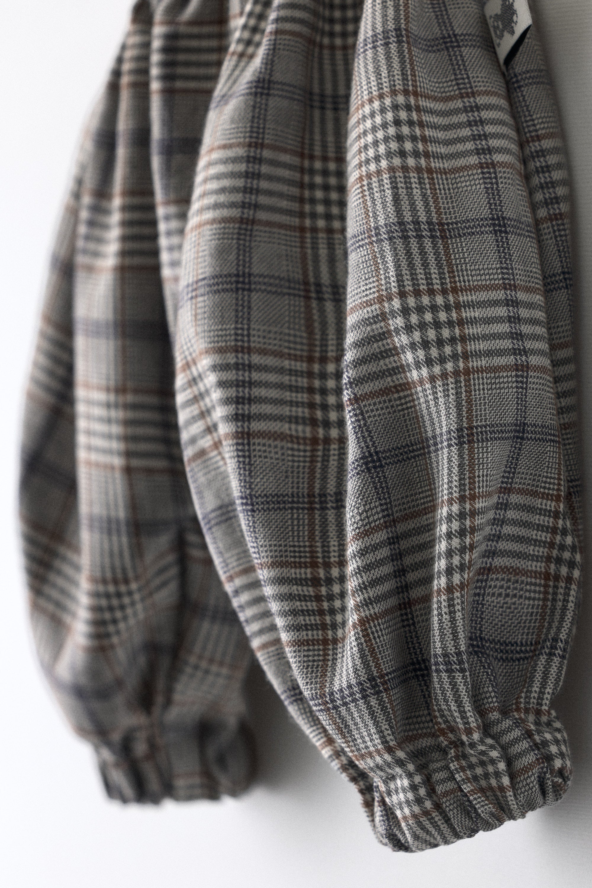 Detalle zoom del tejido de cuadros El Pantalón Balloon Bloom. Marrones, azules grisáceos y blanco roto se entremezclan en su composición auténtica para tu bebé.