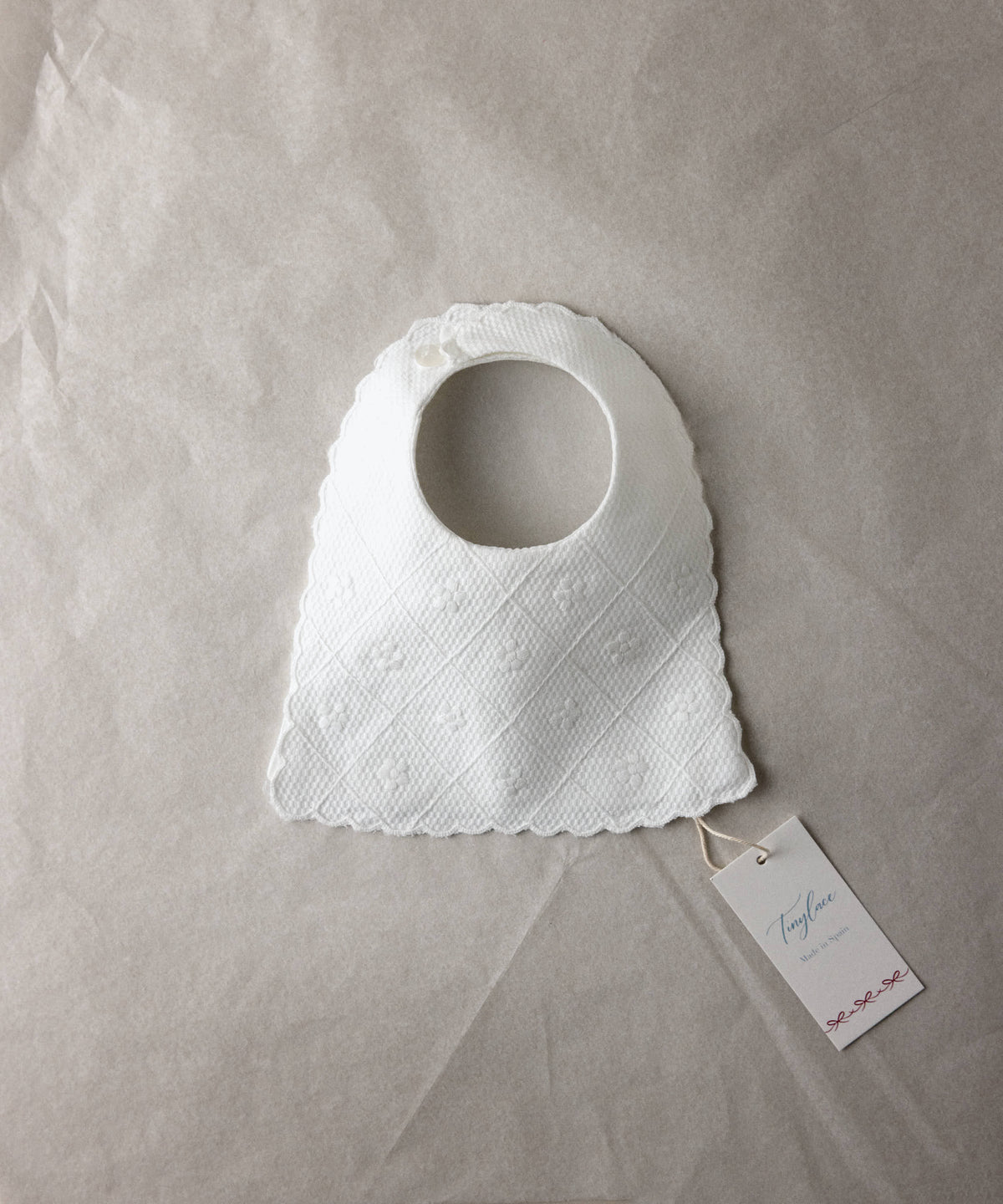 Babero de bebé de piqué blanco bordado Tinylace, presentado en packaging